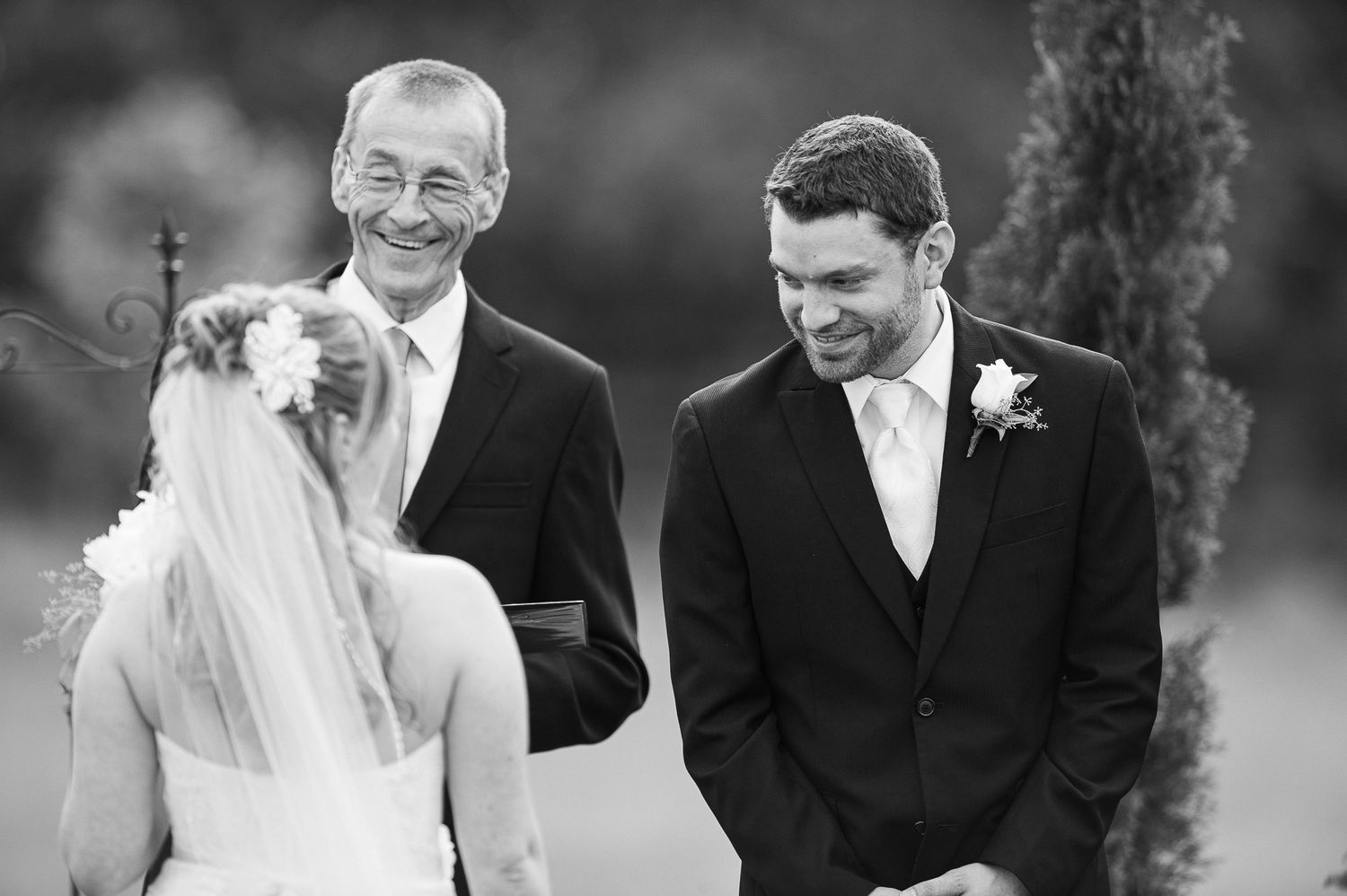 A black and white wedding photograph capturing a joyful moment between the couple.
