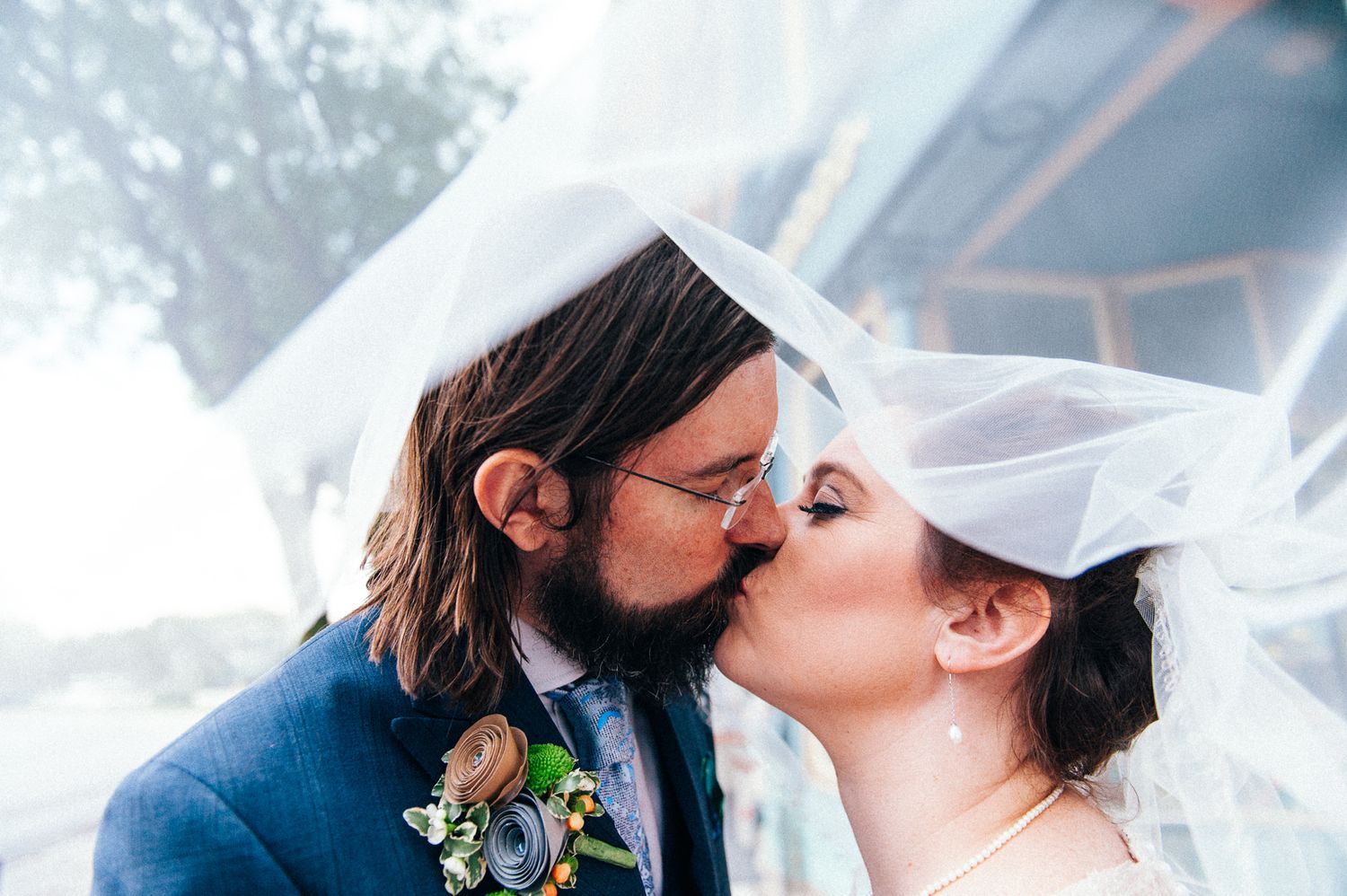 Romantic wedding moment captured through a flowing white veil in natural lighting.