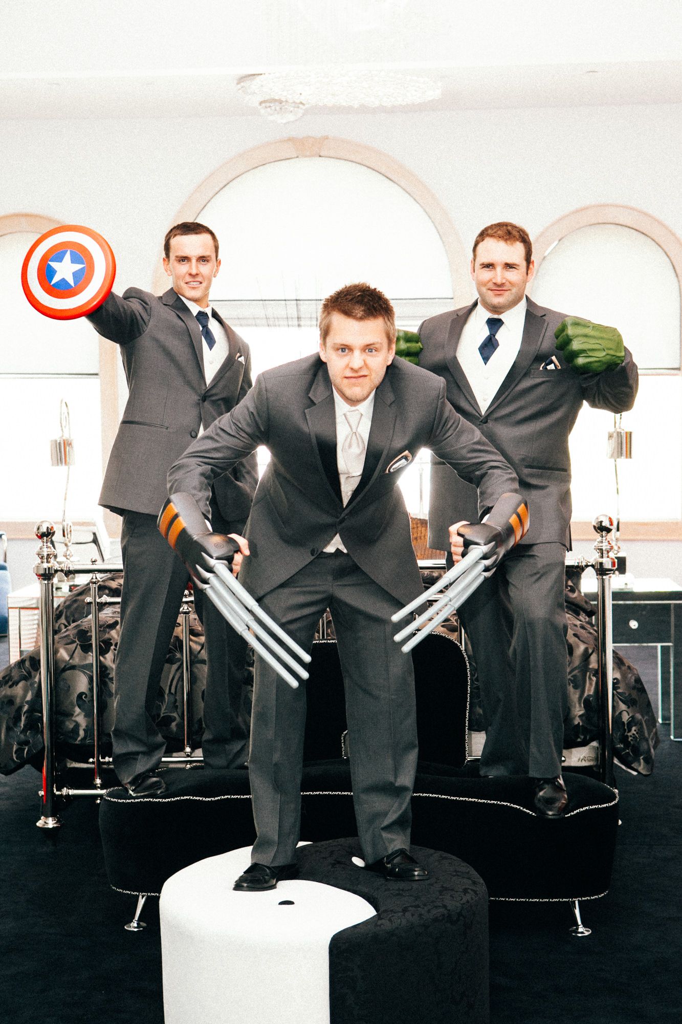 Groomsmen pose playfully with superhero props in a creative wedding photo series.