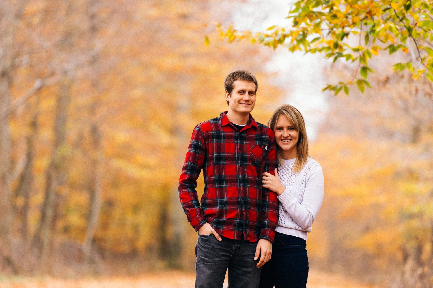 Couple walking together through a park with golden autumn trees.