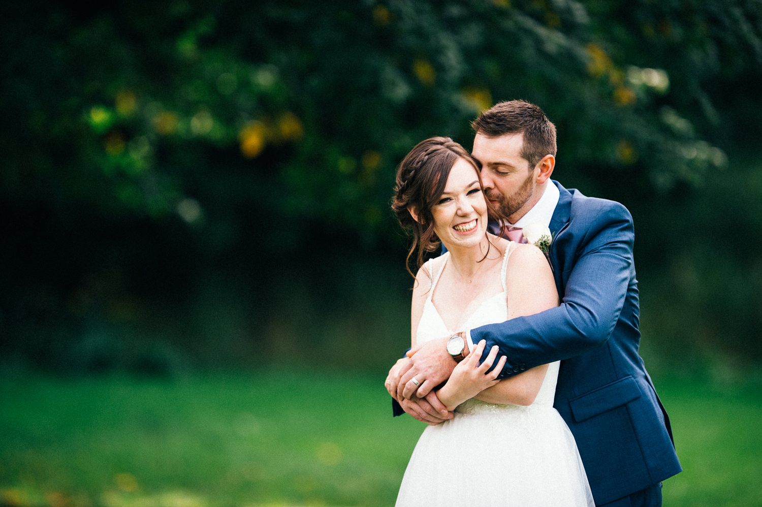 Couple sharing tender moment in garden setting during wedding celebration.