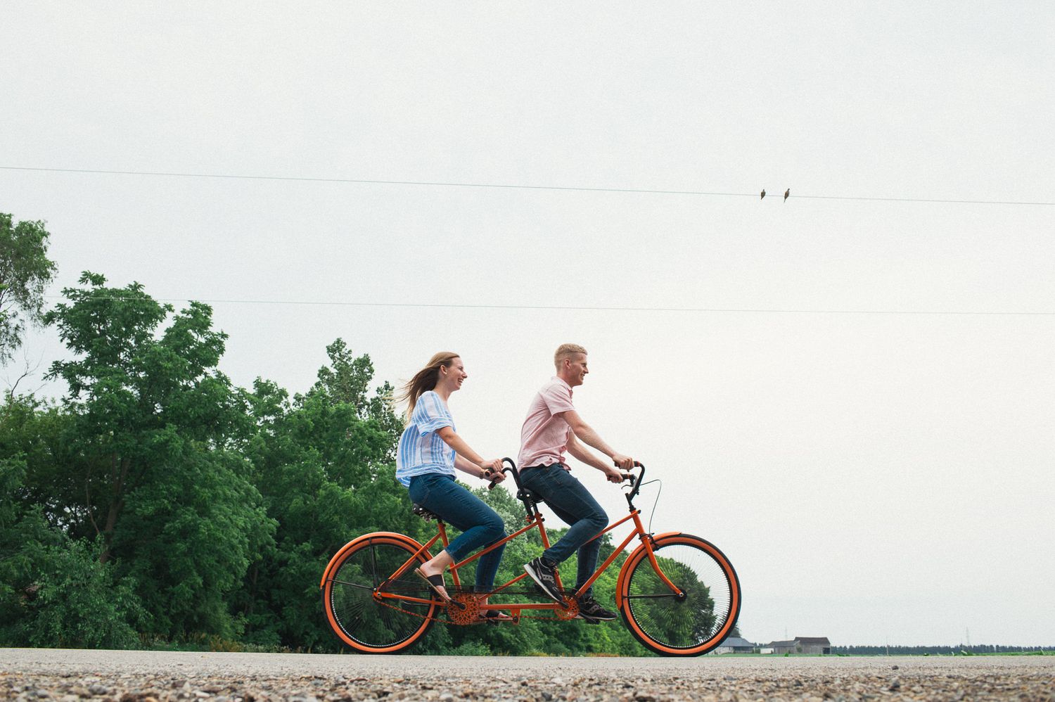 Couple enjoying a tandem bike ride through countryside landscape.