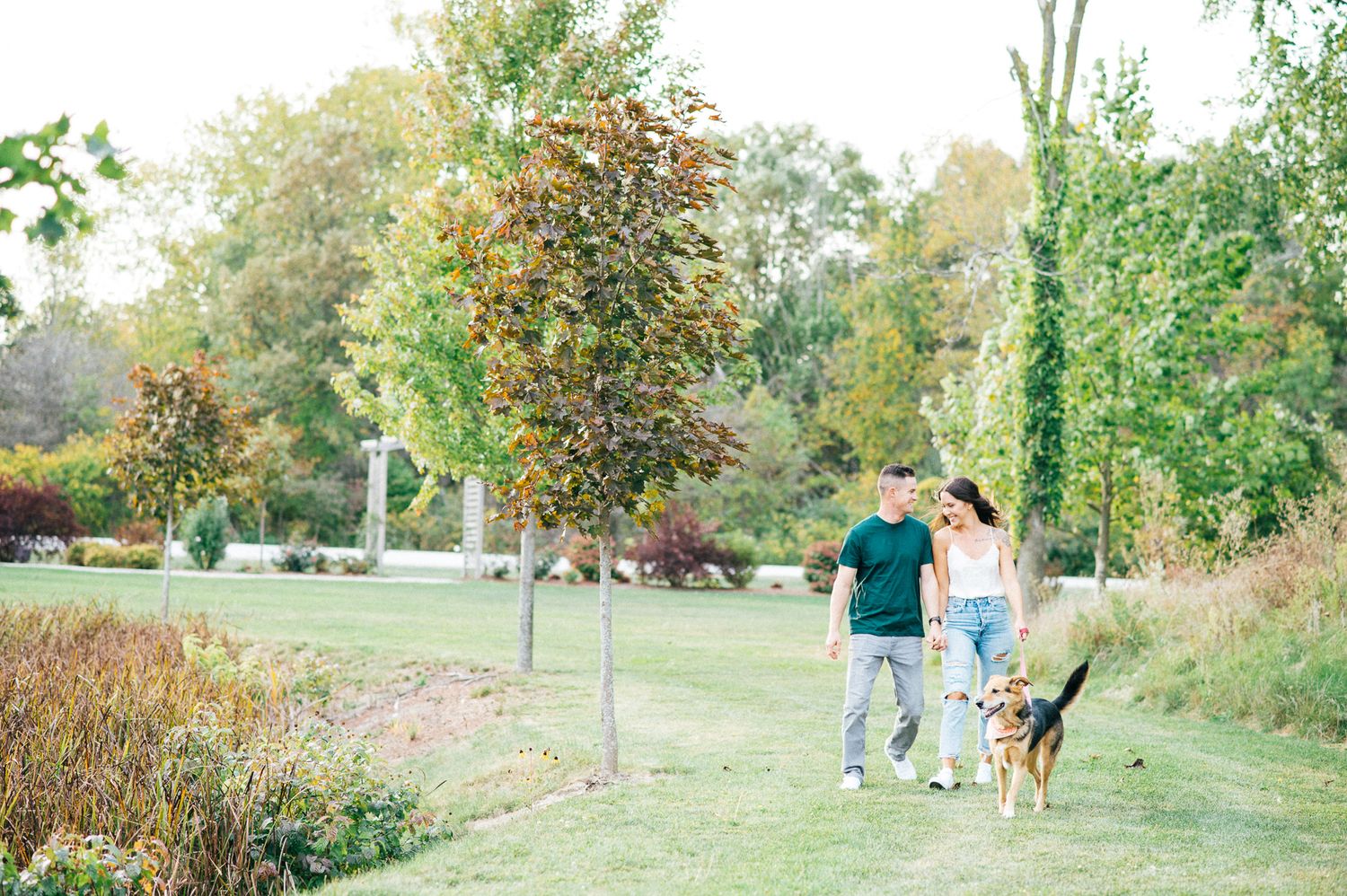 Wide landscape view of couple in outdoor garden setting with greenery.