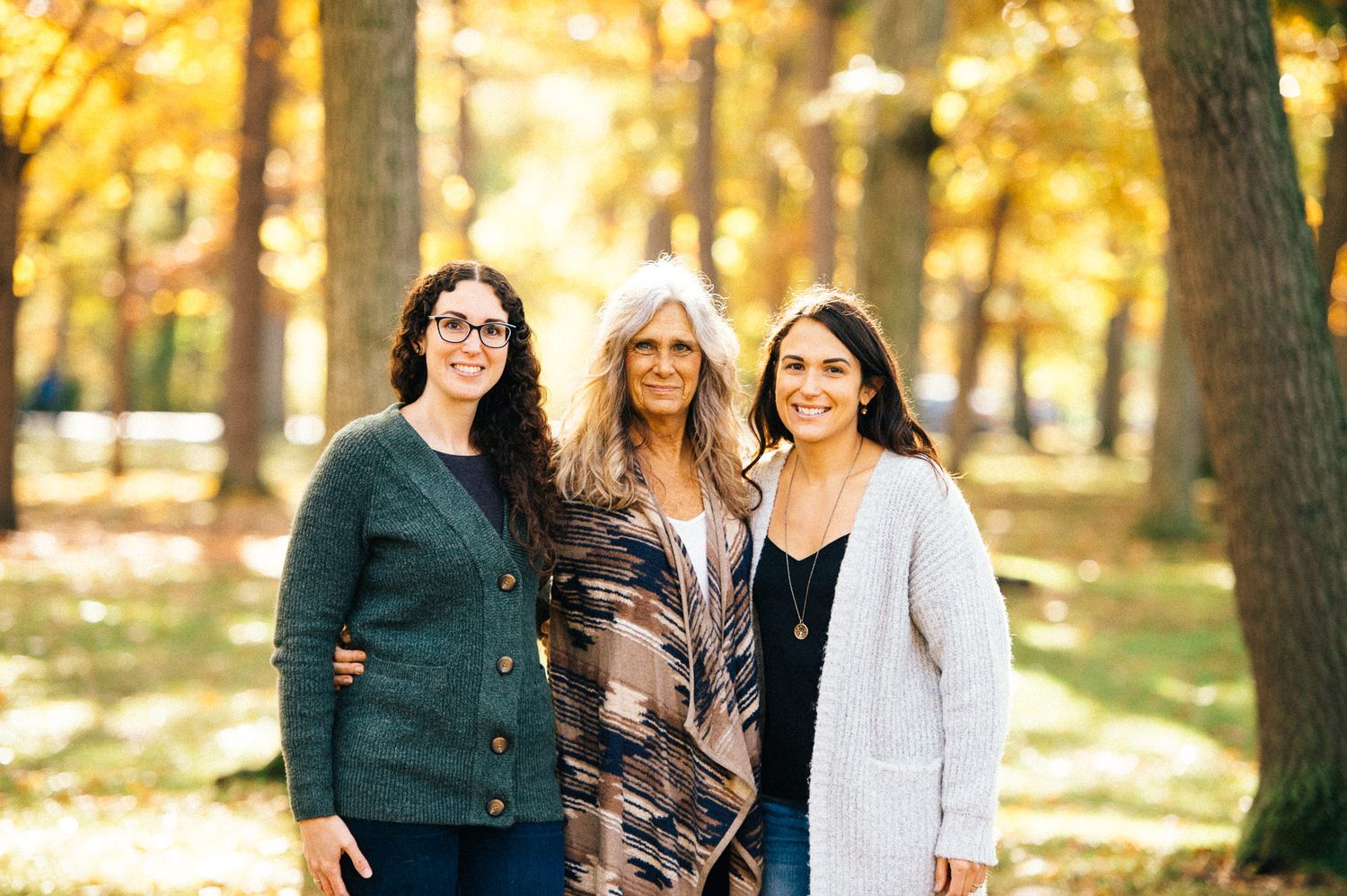 Group of women smiling together outdoors during golden hour in autumn setting.