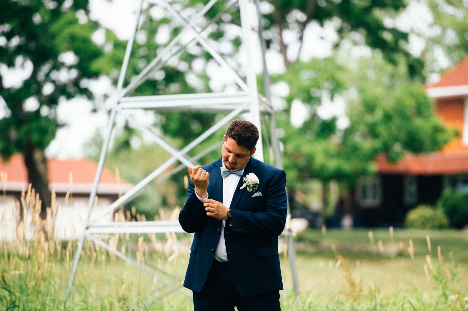 Person in formal attire checks phone near metal structure outdoors.