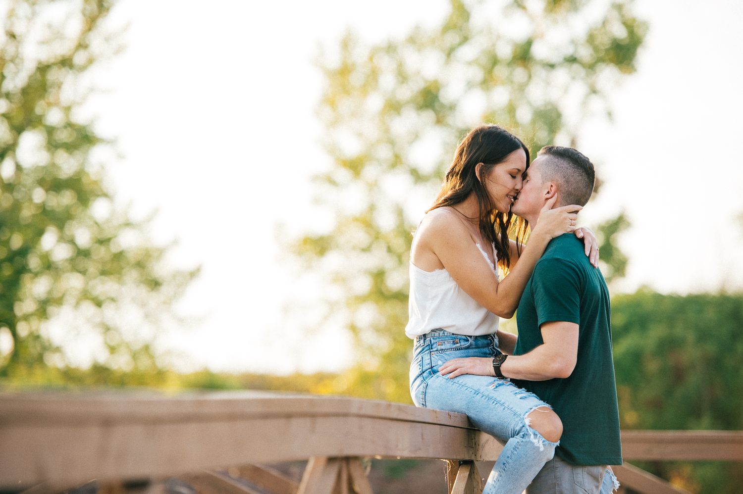 A romantic sunset moment between a couple on a wooden structure.