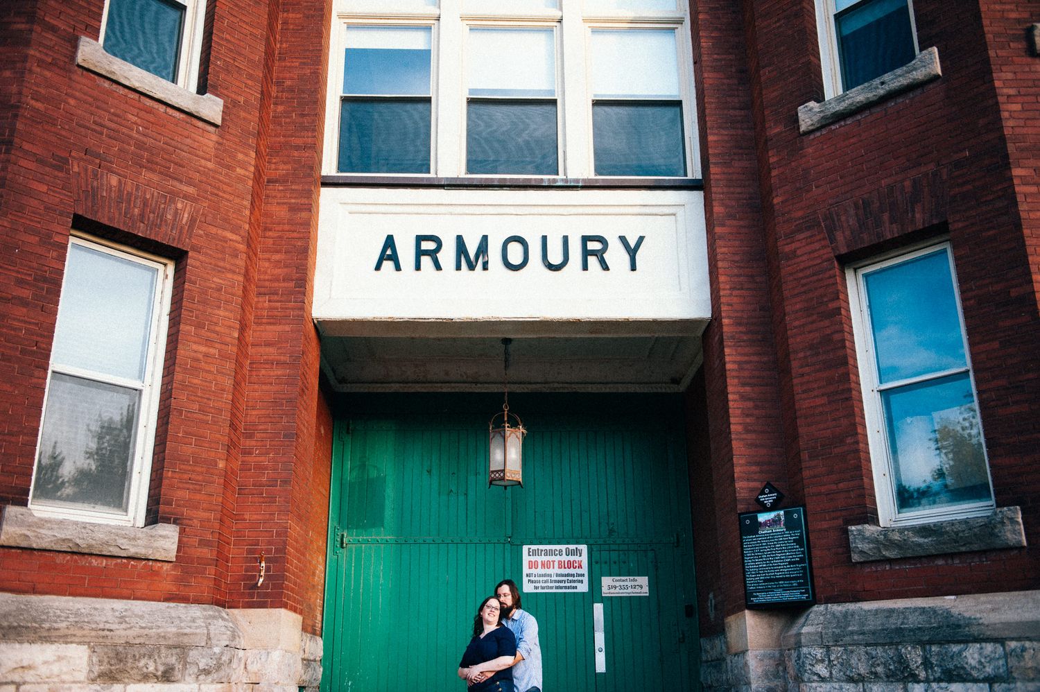 Red brick building exterior with green doors and Armoury signage.