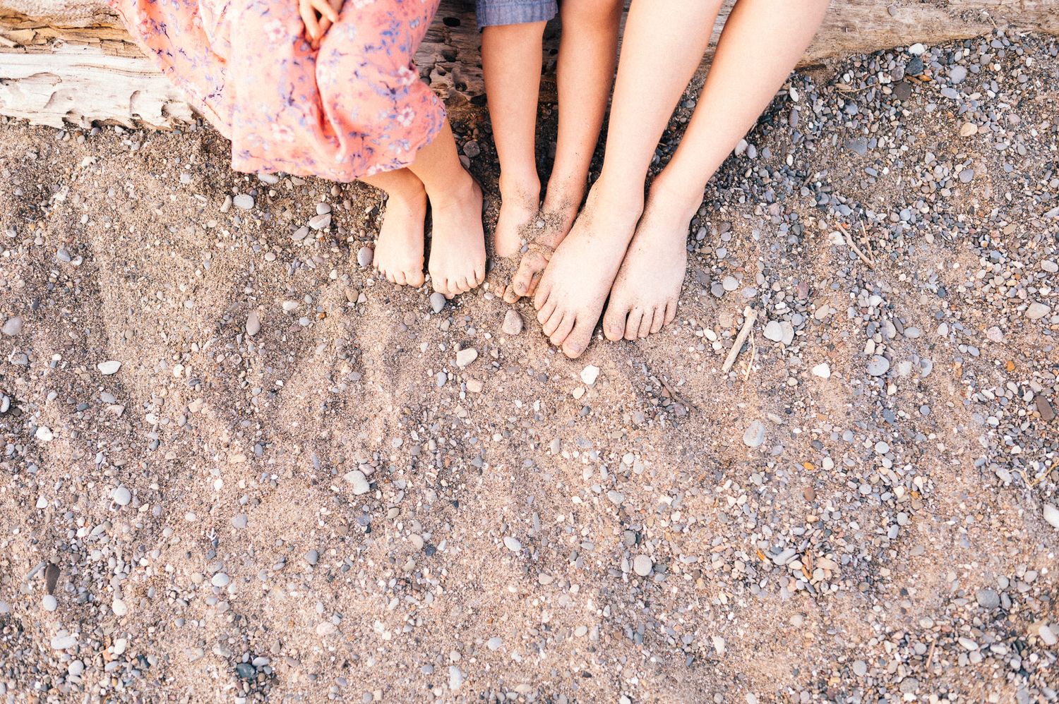 Close-up view of bare feet resting on rocky beach surface.