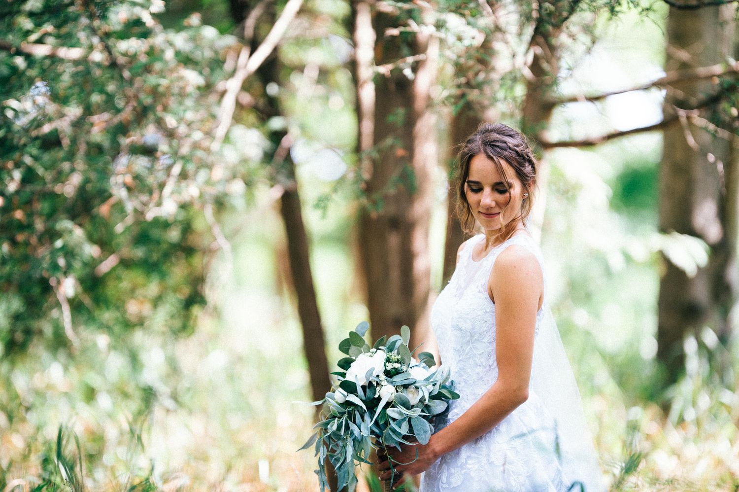 Elegant outdoor wedding photography session among green trees and natural light.