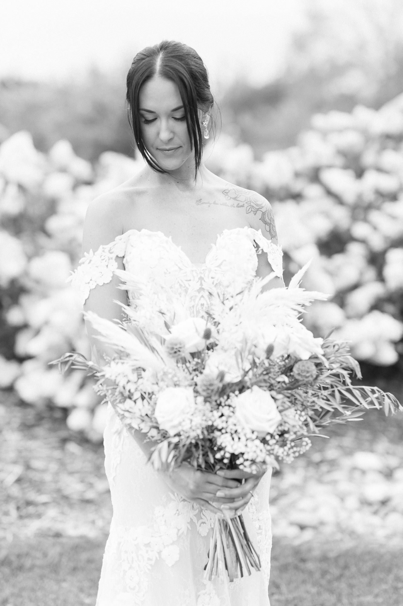 Ethereal black and white portrait of bride holding a romantic white and green bouquet.