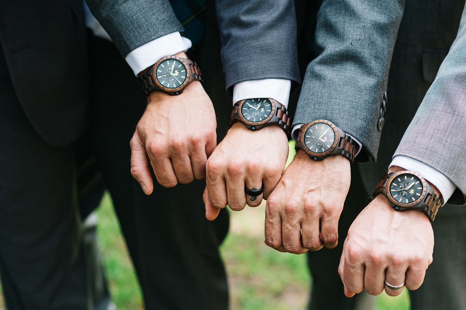 Close-up detail shots of groomsmen's matching watches and suit sleeves at a formal wedding.