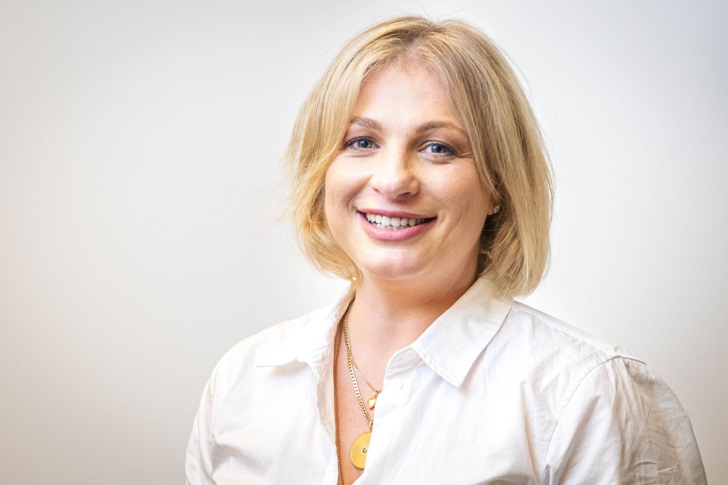 Professional headshot photos of a woman in white business attire smiling against a light background.