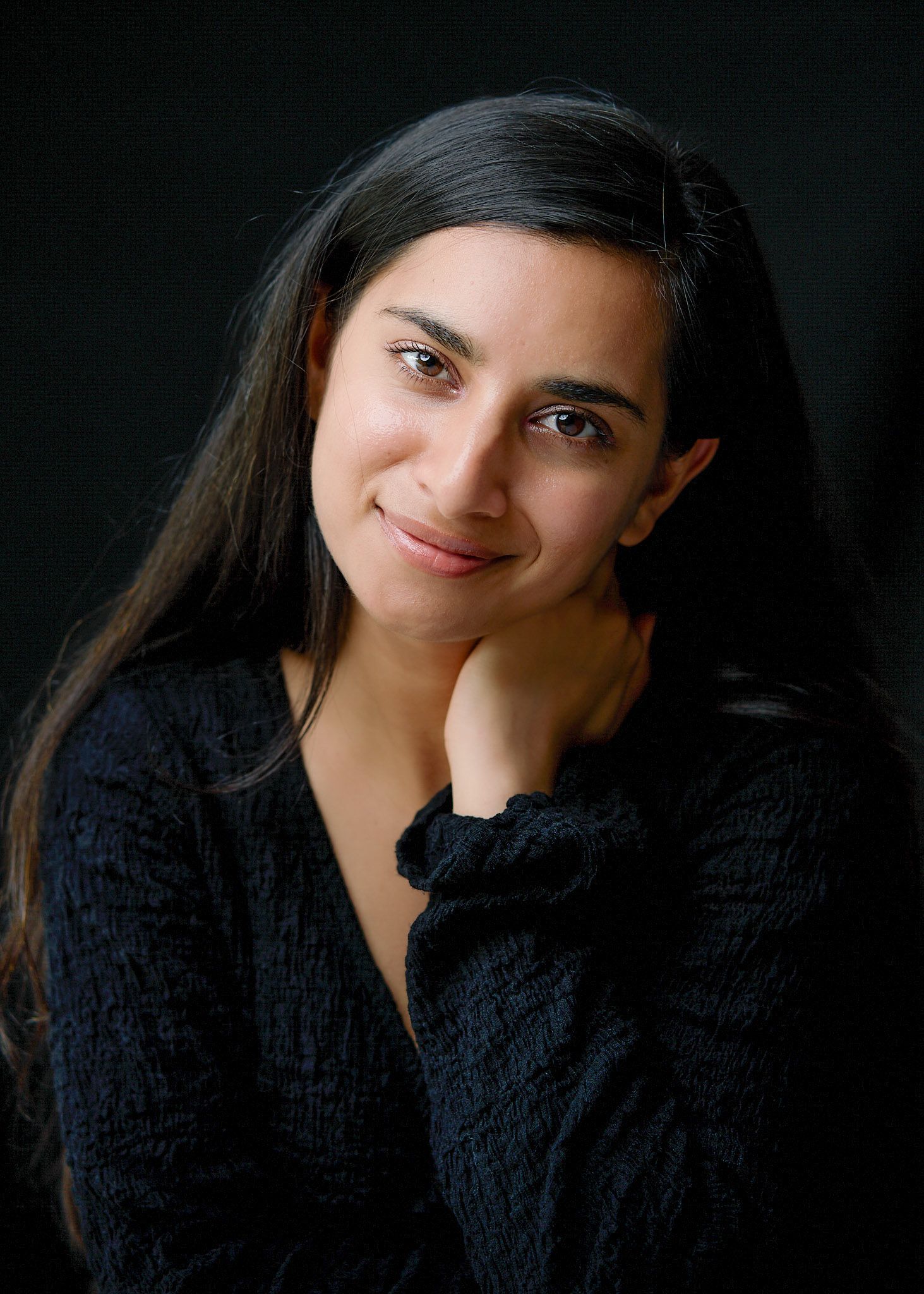 Professional headshot showing someone in a black sweater against a dark background with varying expressions.