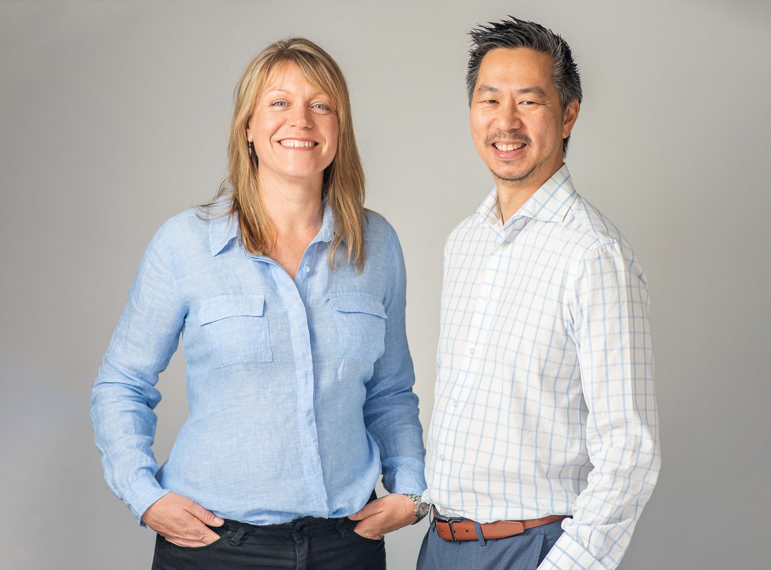 Professional headshot of two colleagues in business casual attire against a gray background.
