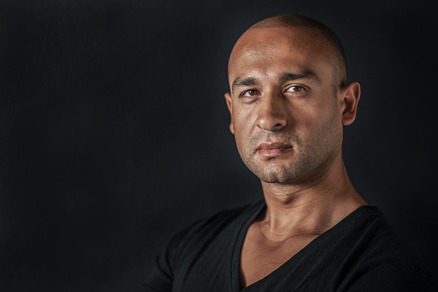 Dramatic black and white portrait of a man against dark background.