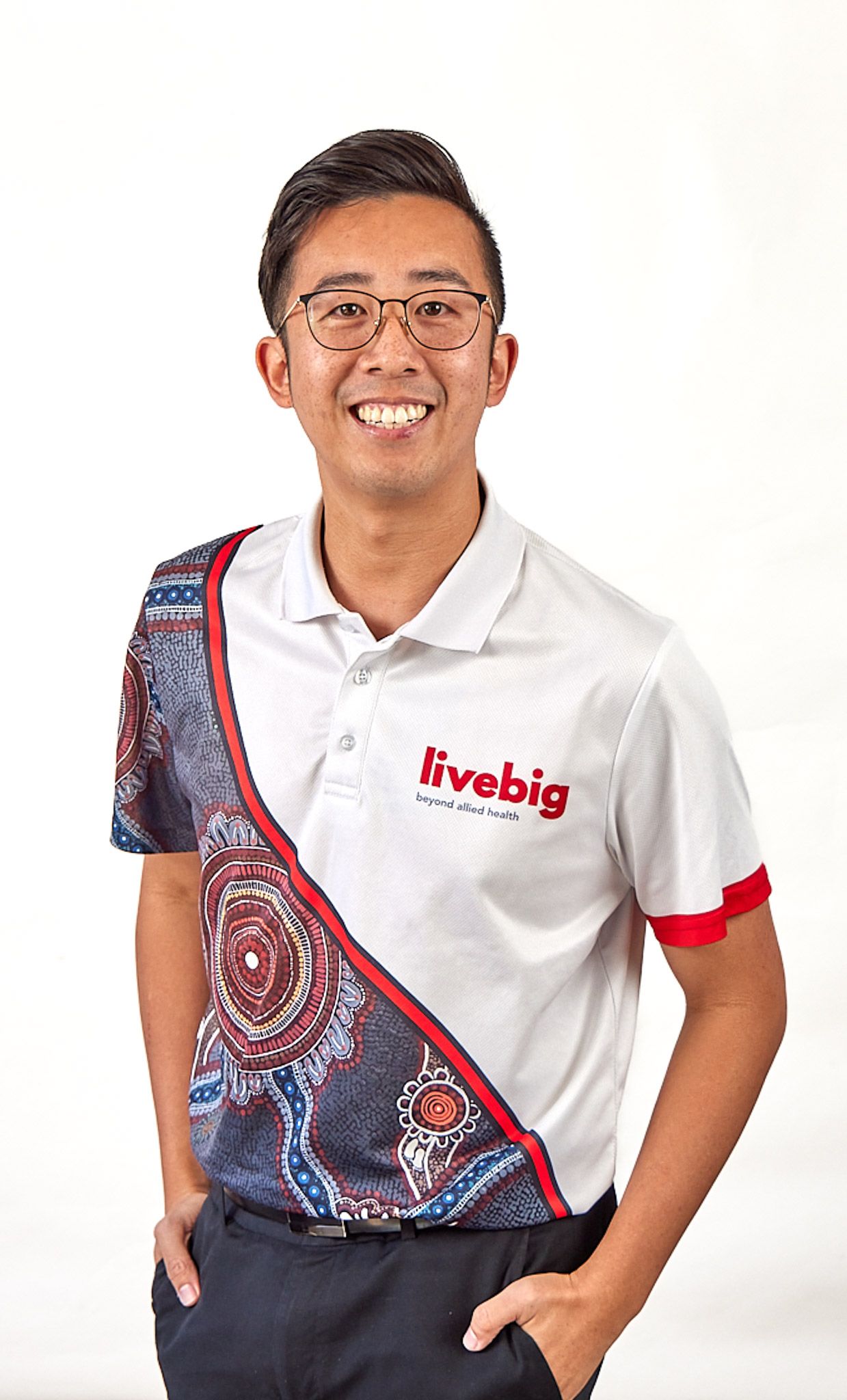 Corporate headshot of person in white LiveBig polo shirt with decorative pattern detail.