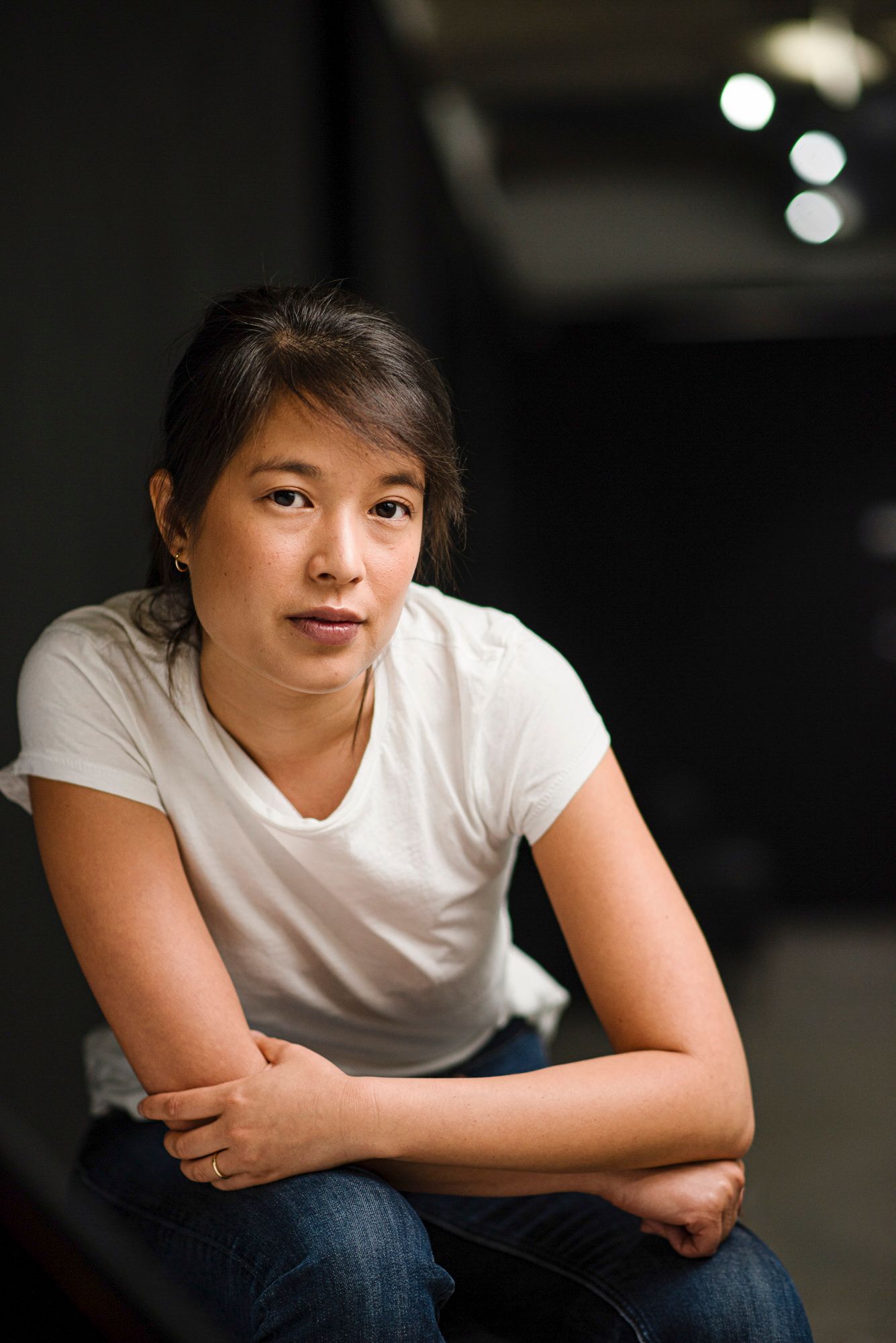Casual portrait of person in white t-shirt and jeans against dark background.