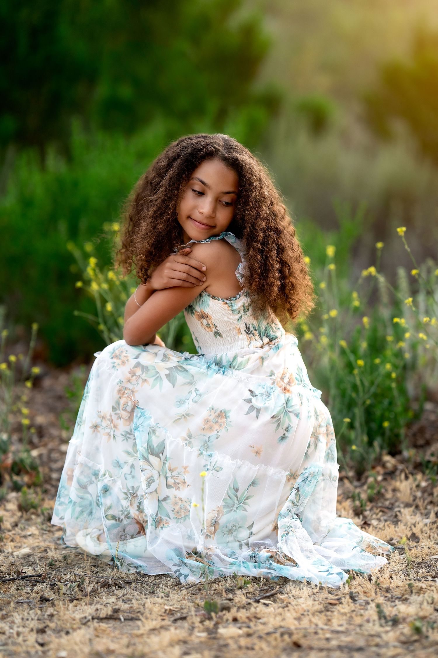 Elegant floral dress photographed in golden sunlight against lush green nature backdrop.