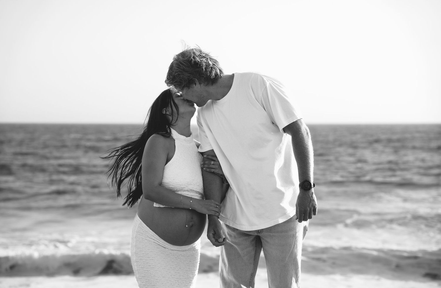 Black and white beach maternity photos showing silhouettes against ocean backdrop.