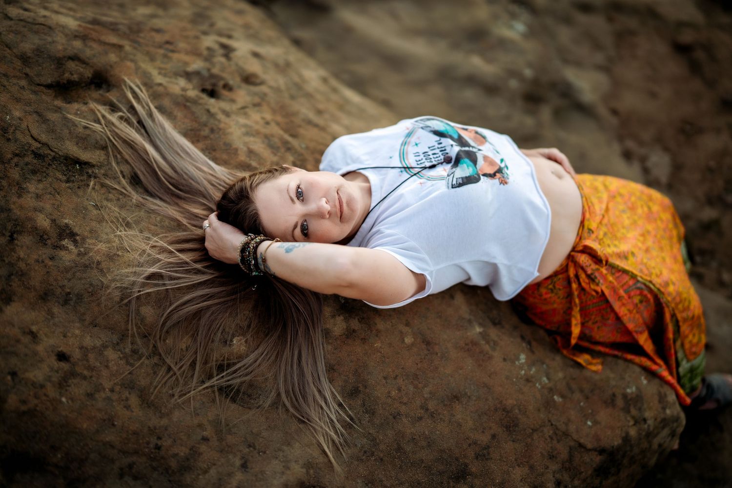 A series of artistic portraits shows someone lying on rocky terrain at sunset.