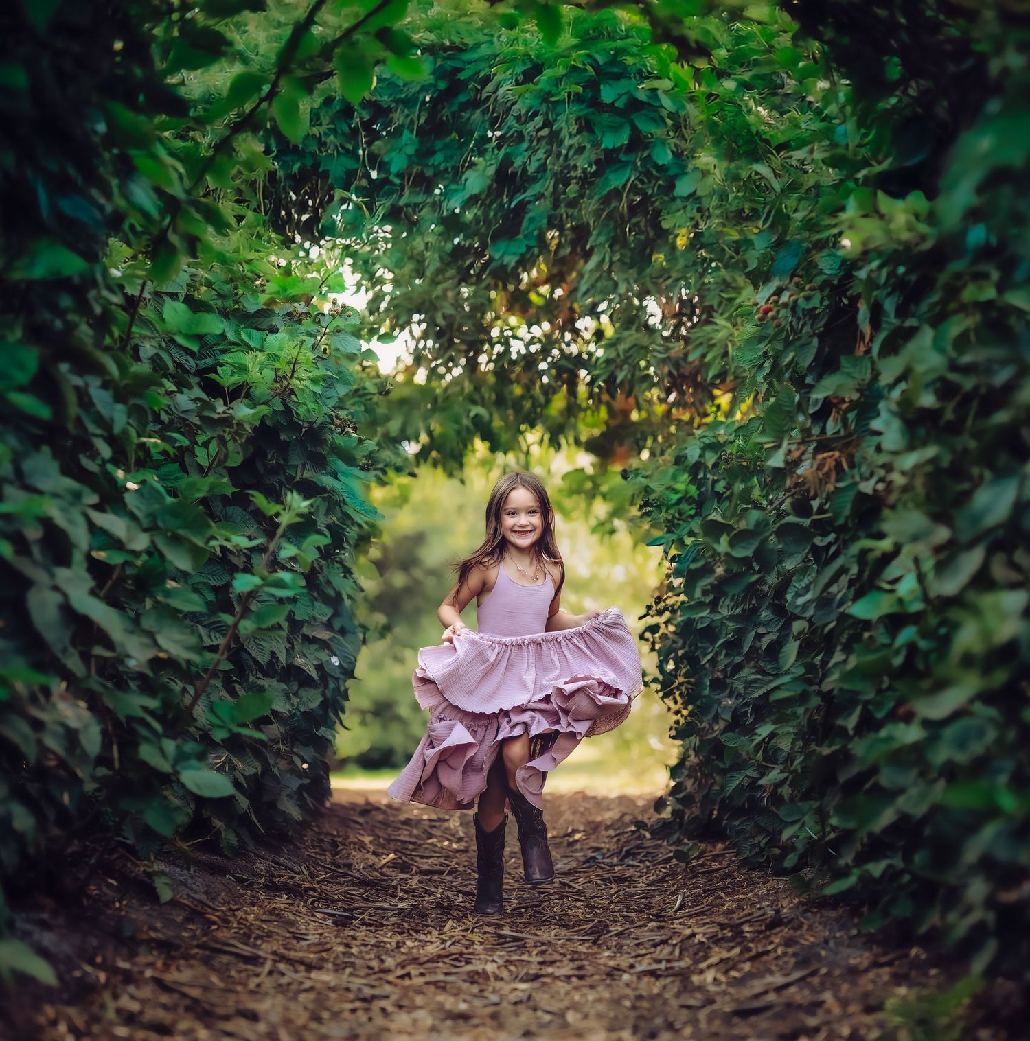 A twirling dress creates movement in a magical garden tunnel framed by green leaves.