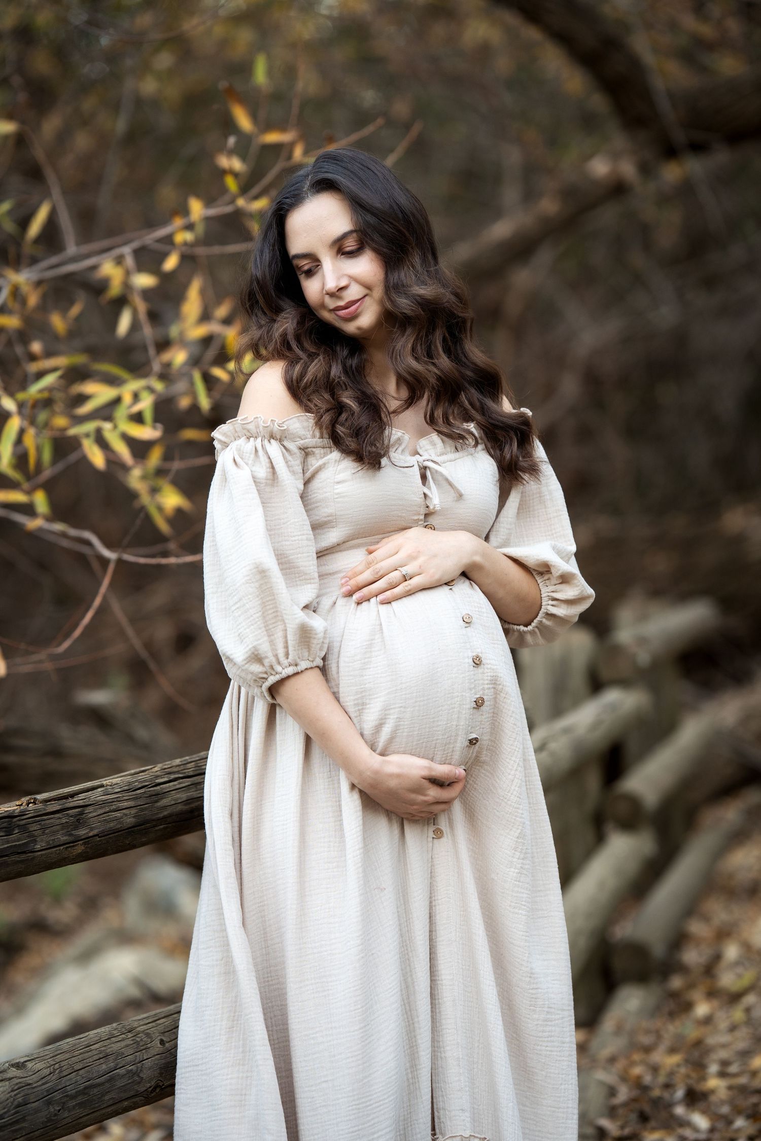 Natural light maternity portraits featuring white dress and autumn woodland scenery.