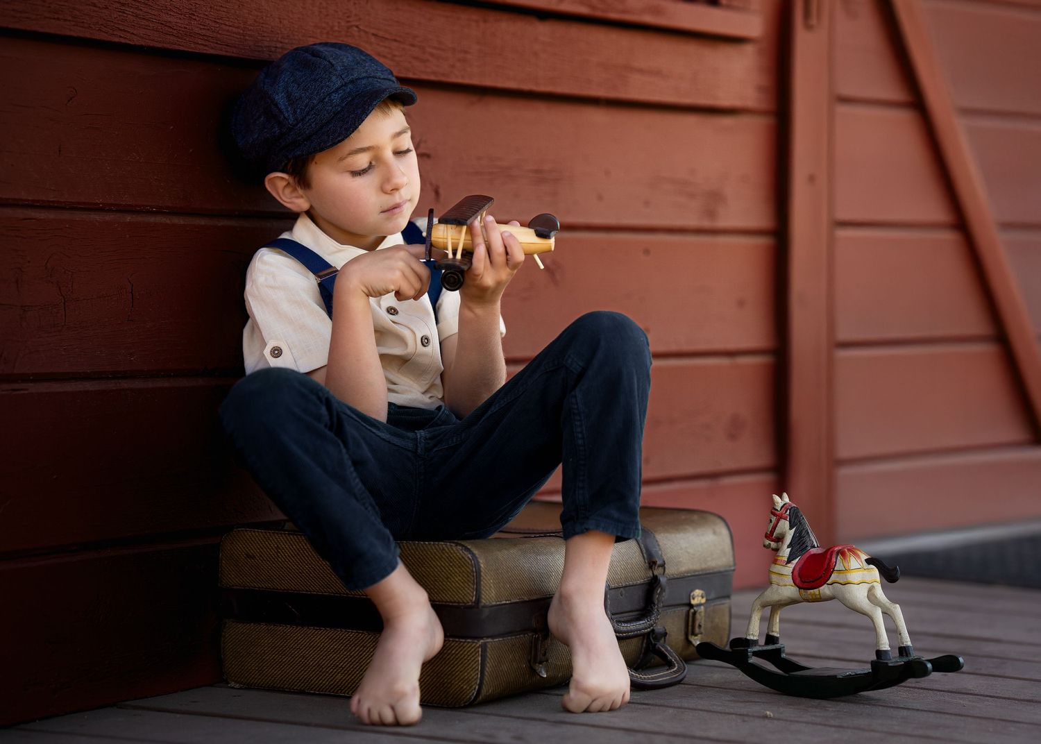 Child in casual attire sitting on wooden steps with vintage toys.