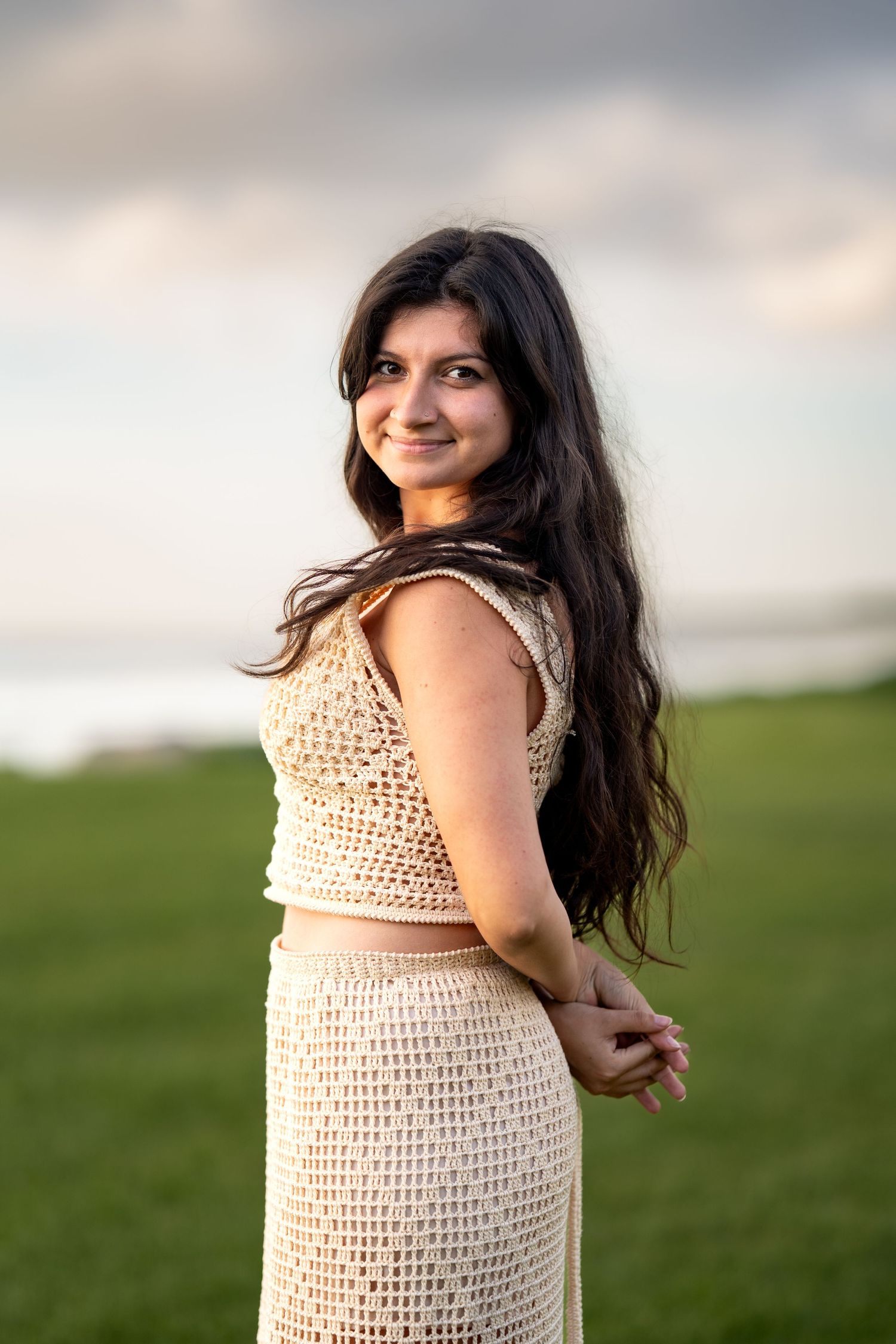 Woman wearing a crochet dress poses in an outdoor setting with natural lighting.