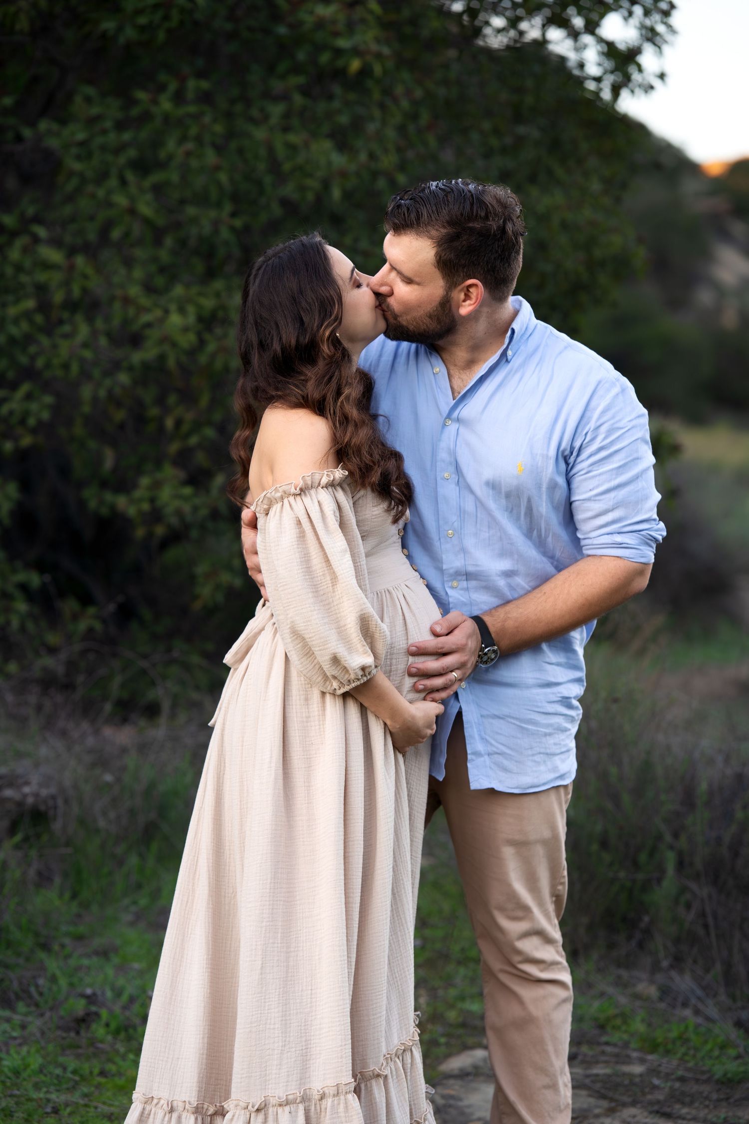 Intimate maternity photos of couple sharing tender moments in natural outdoor setting.