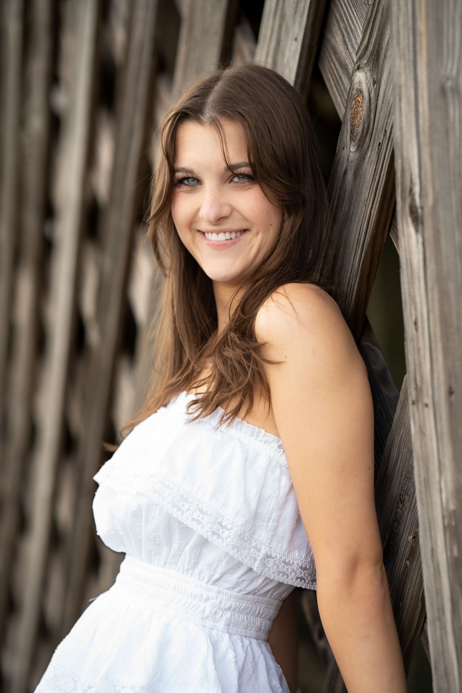 Rustic barn wood backdrop portrait session in white summer dress.