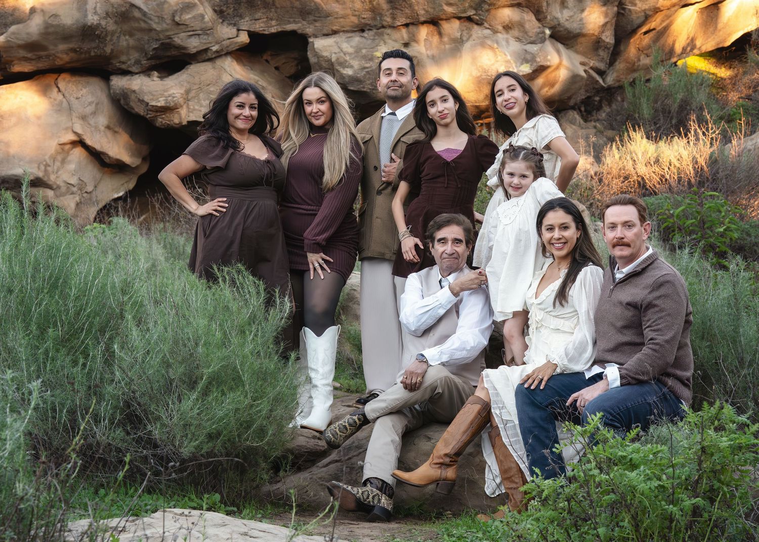 Group portrait of friends and family gathered together against a rocky backdrop at sunset.
