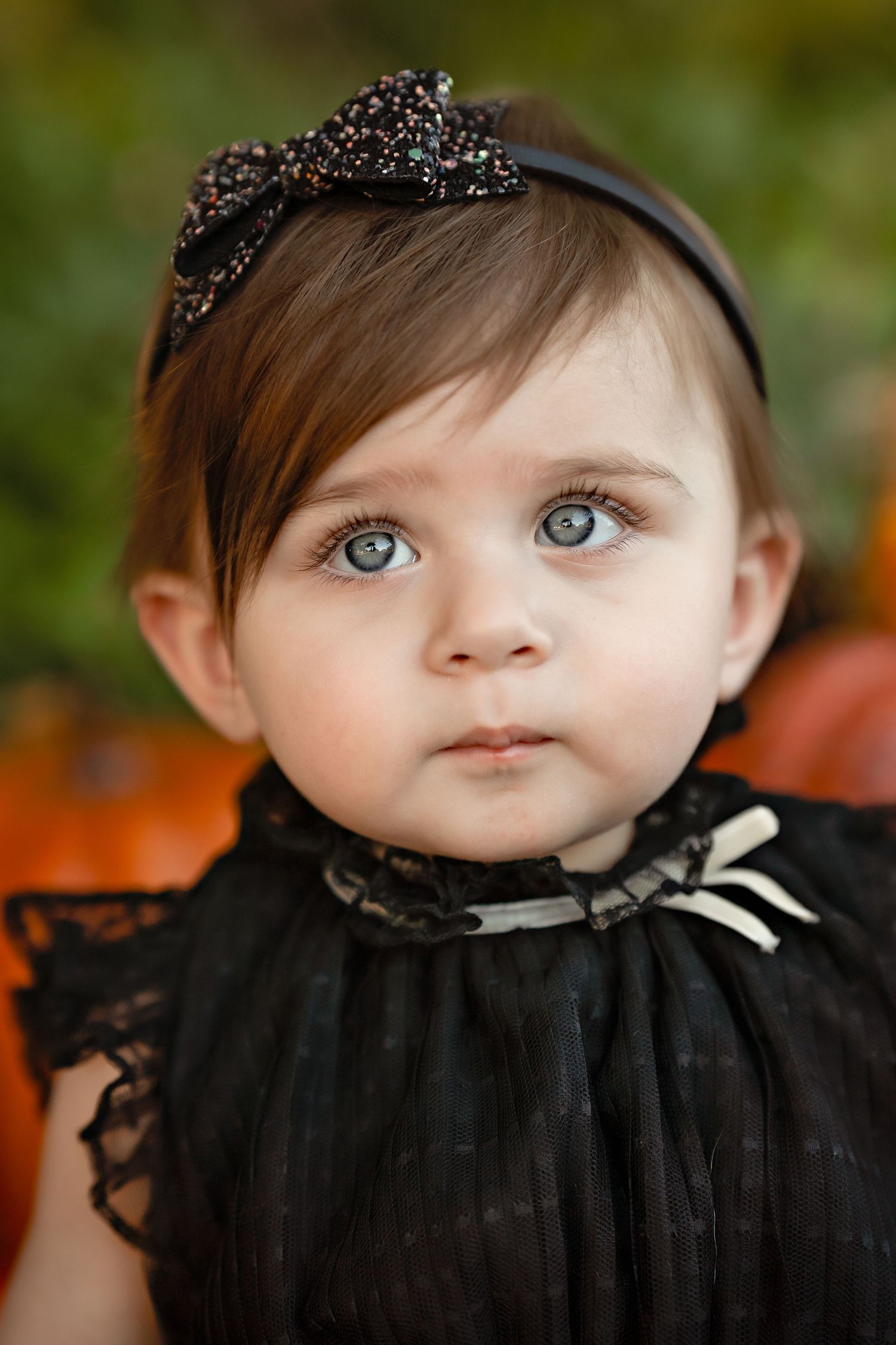 Close-up portrait of baby wearing black lace dress and sparkly headband.