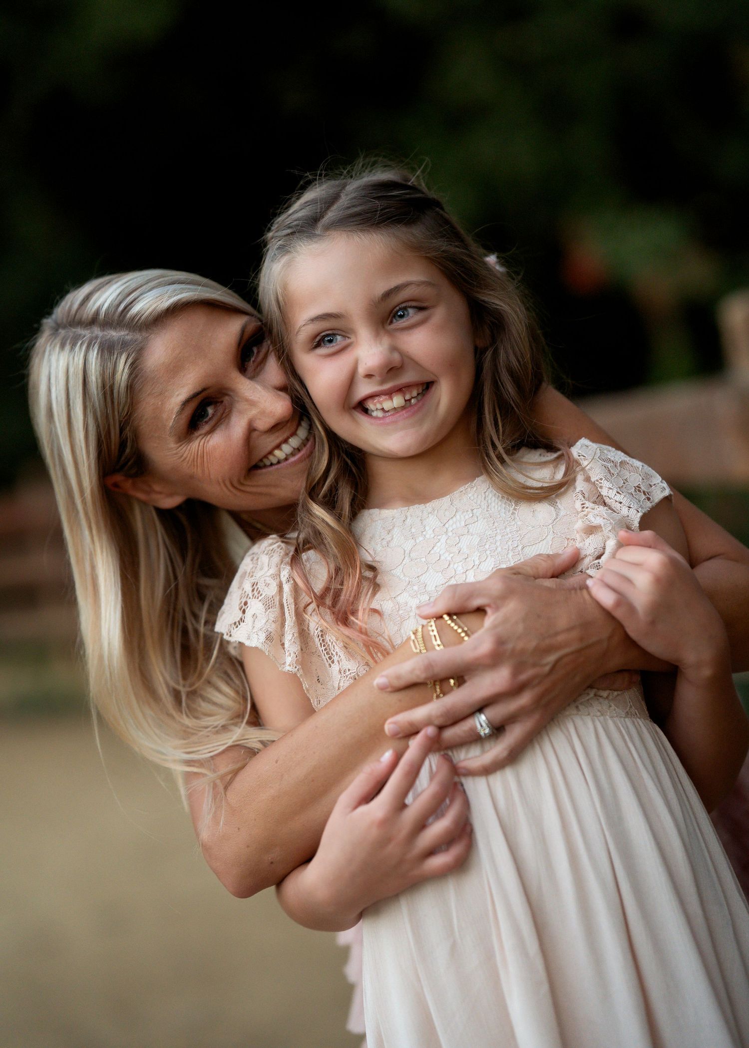 A tender embrace is shared between two people wearing light-colored clothing against a natural background.