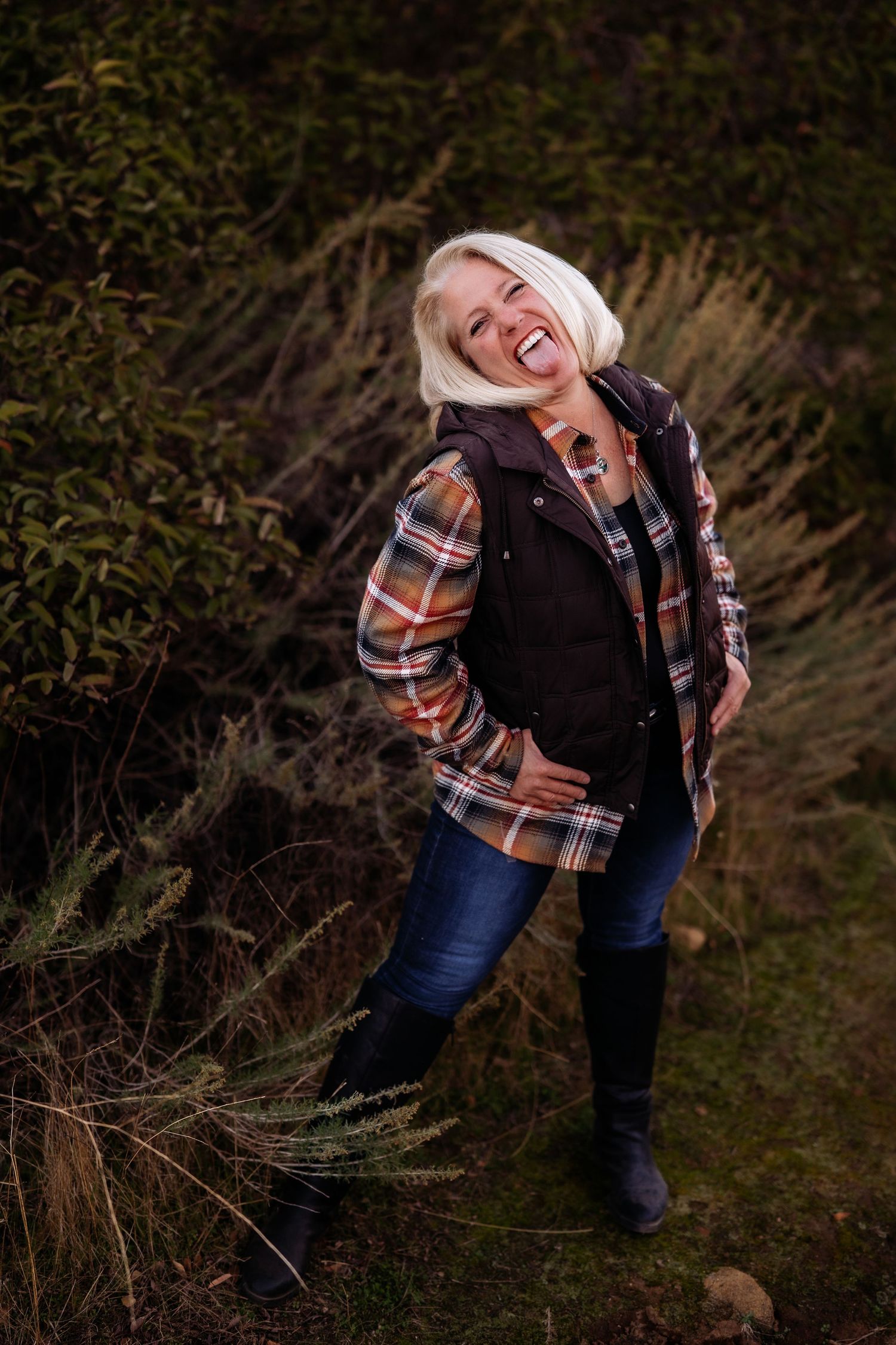 Playful outdoor photoshoot featuring plaid flannel and jeans against a natural backdrop.
