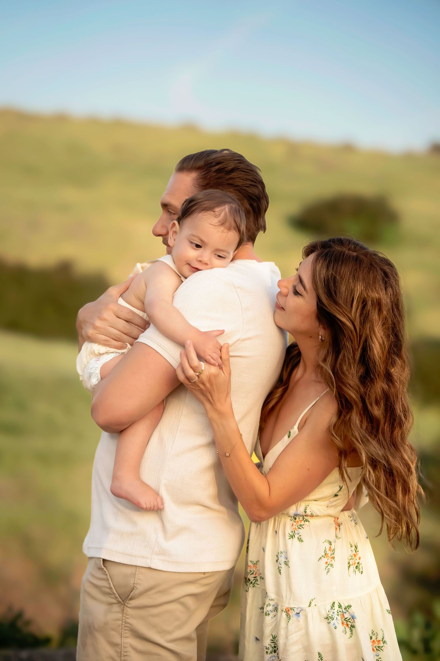 Tender family moment captured against rolling hills during golden hour.