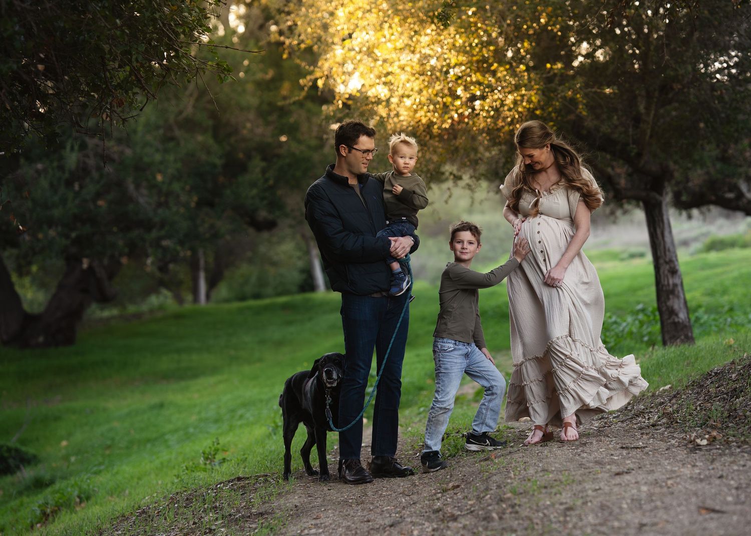 Family and dog enjoying outdoor photography session in golden evening light.