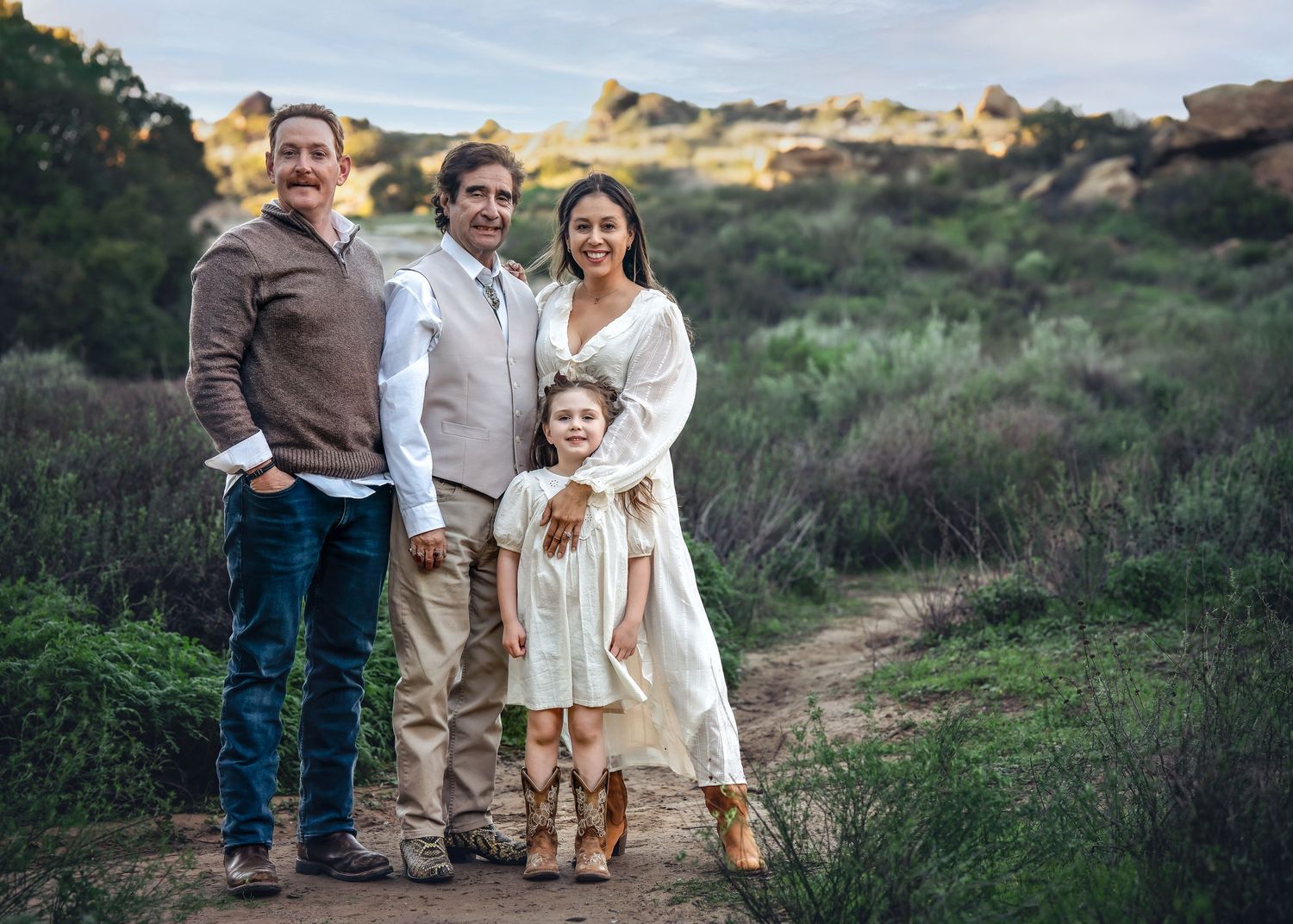 Family in casual attire poses together on a nature trail with scenic coastal views.