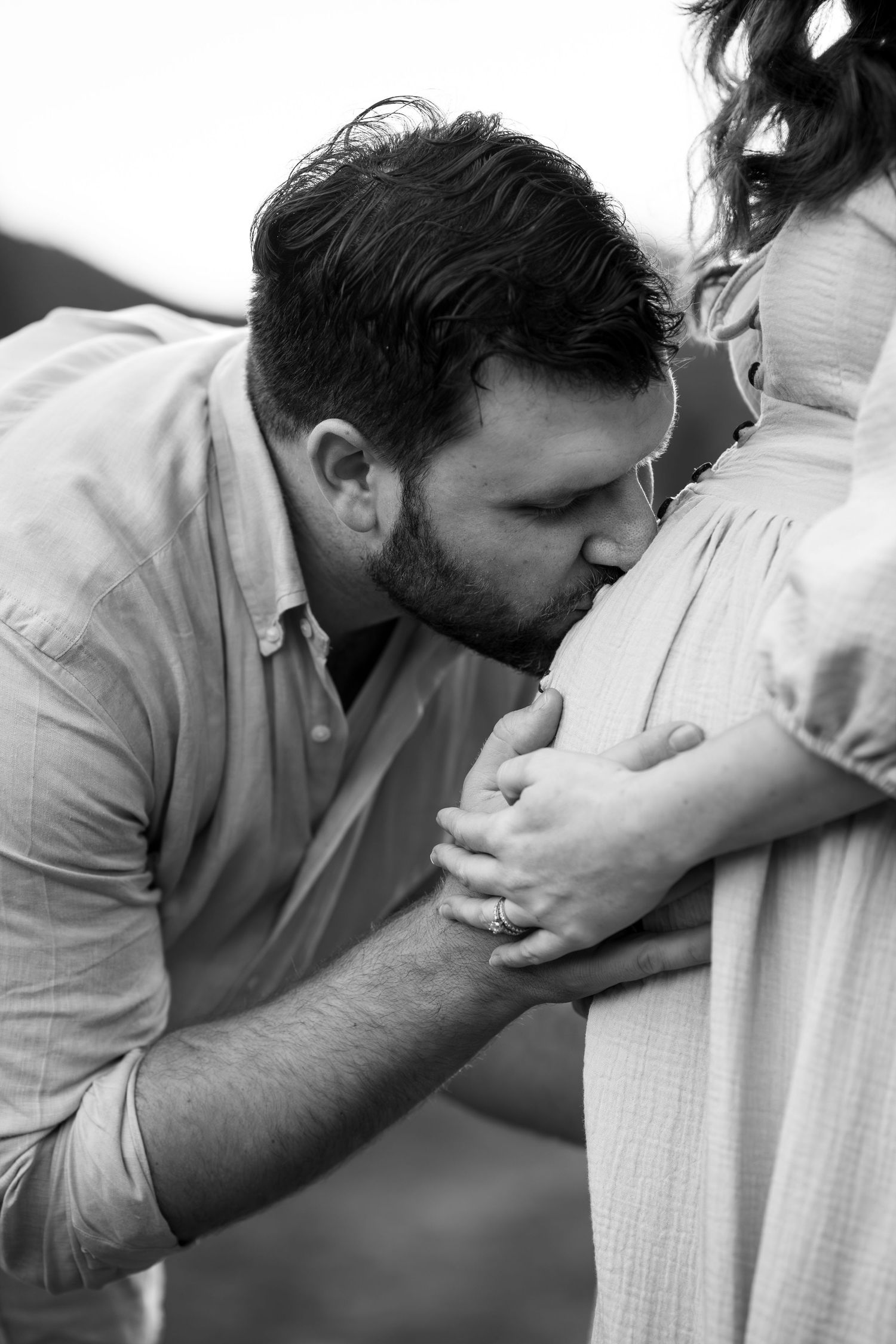 Intimate black and white maternity photo showing tender moment with pregnant belly.