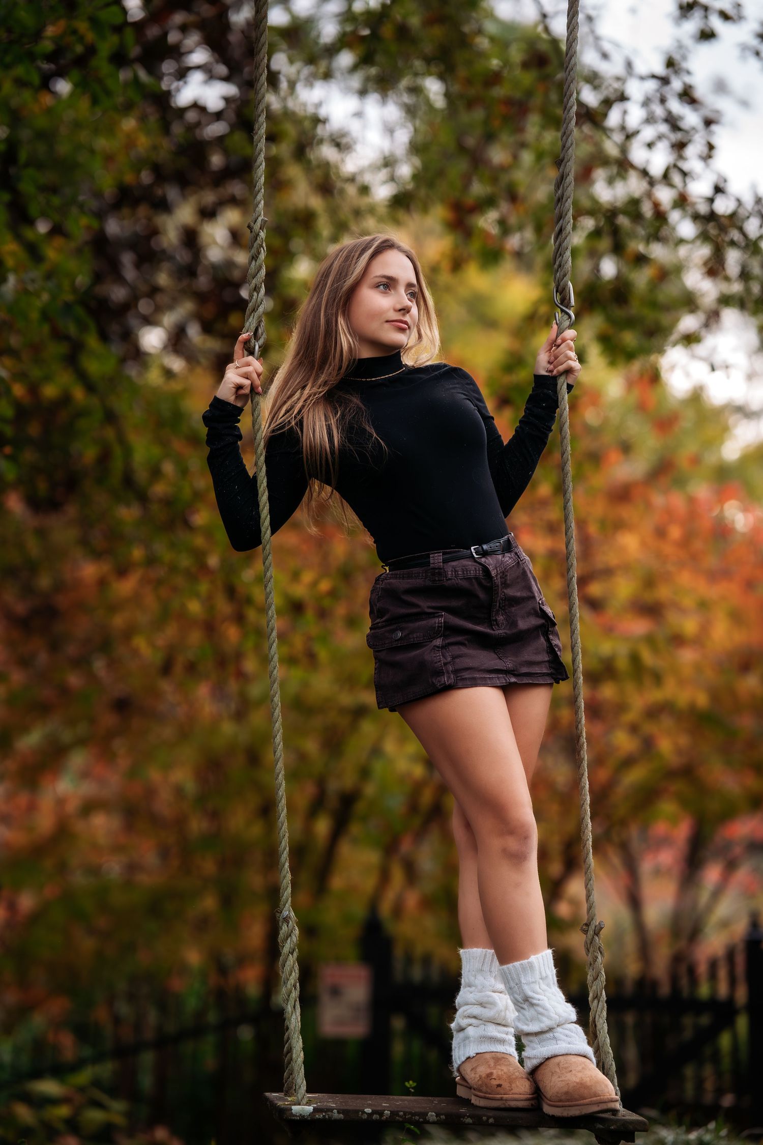 Autumn outdoor portrait session on rope swing with fall foliage in background.