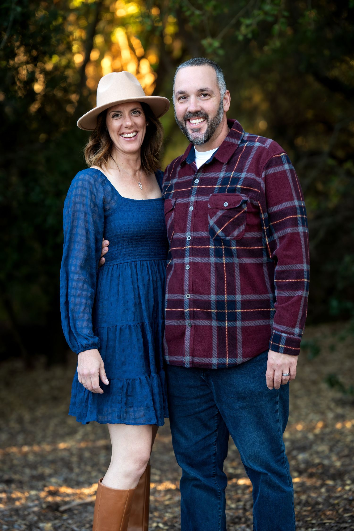 Couple in casual autumn attire smiling together in golden sunset light.
