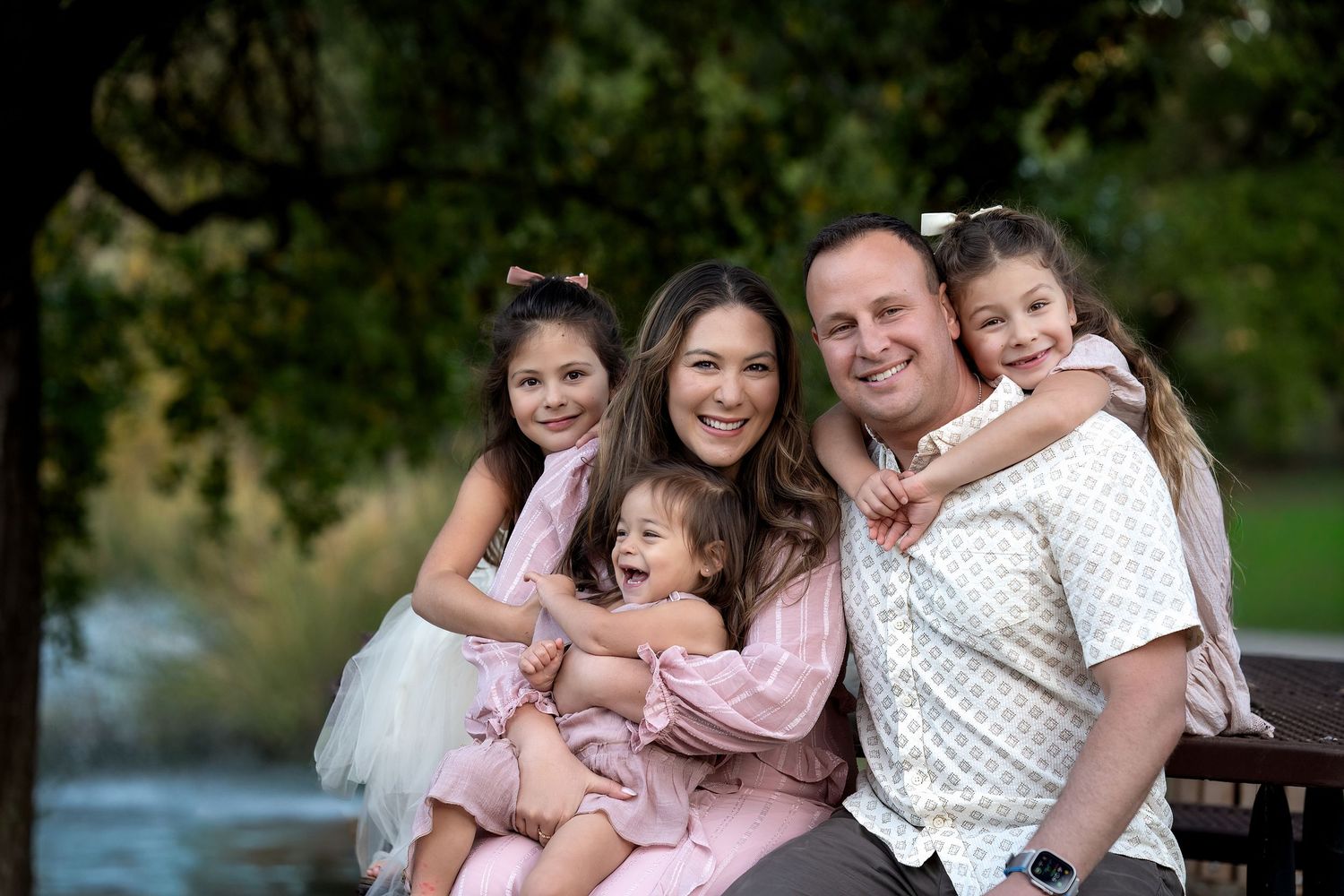 Happy family sitting together on bench near water.