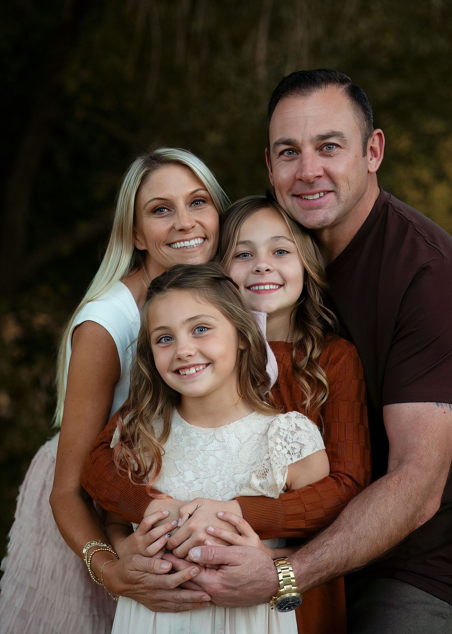 Family portrait series in coordinated outfits against natural outdoor backdrop.