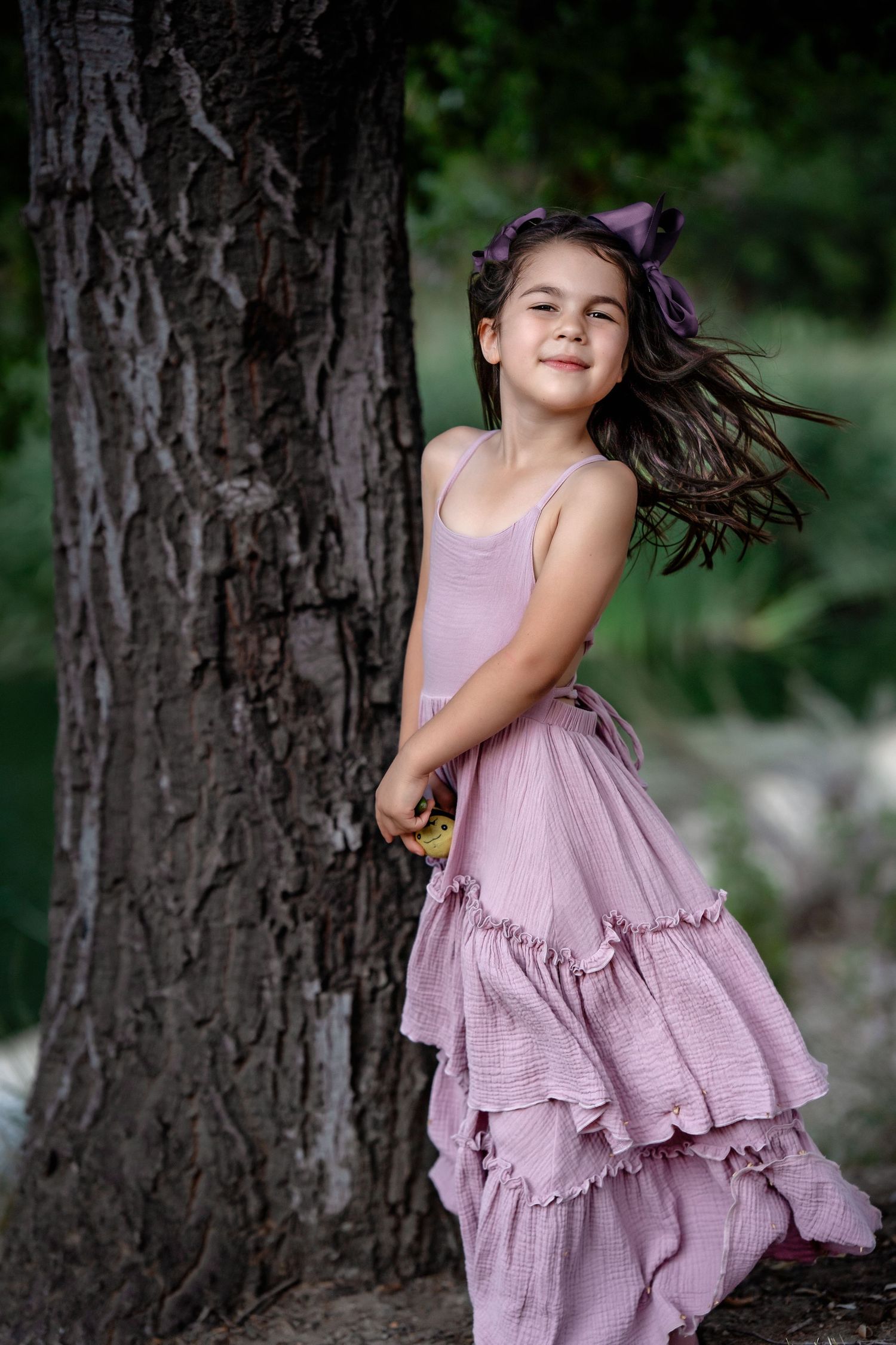A purple ruffled dress twirls in motion against a natural outdoor background.