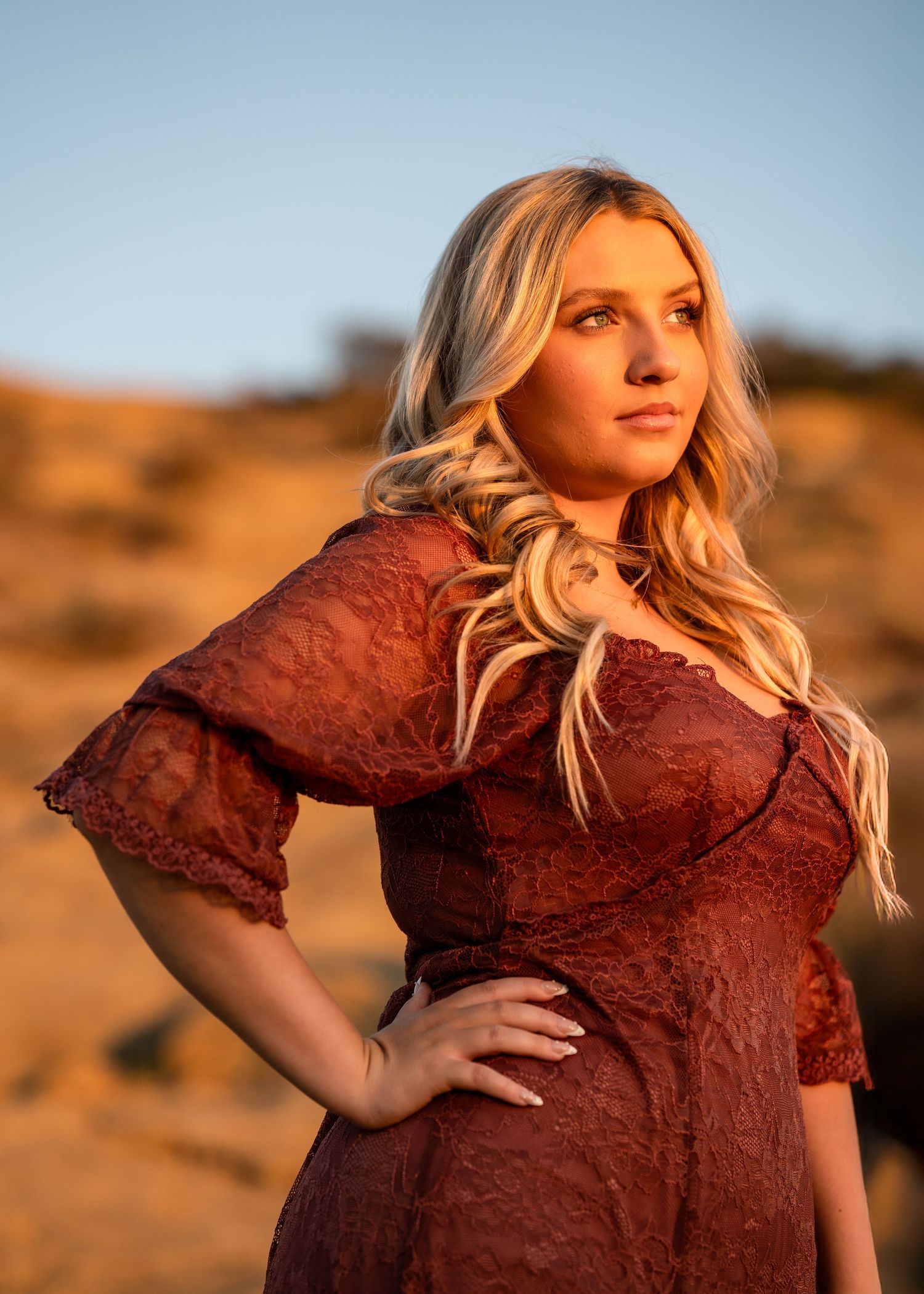 Desert sunset portrait session featuring burgundy lace dress and dramatic lighting.