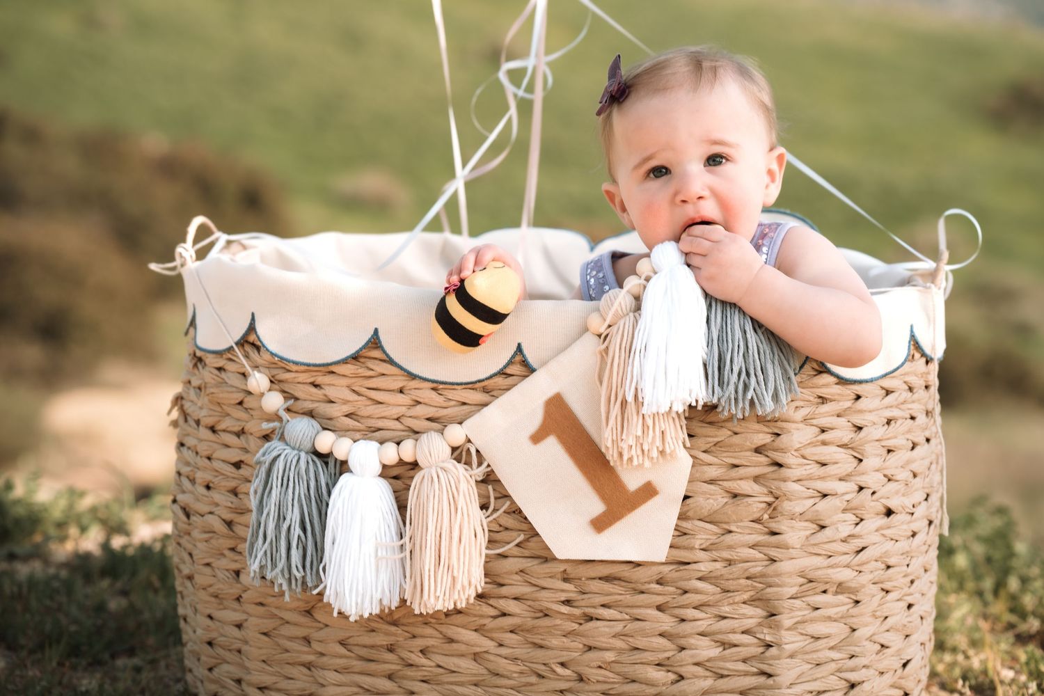 Baby sitting in woven basket with decorative accessories for milestone photoshoot.