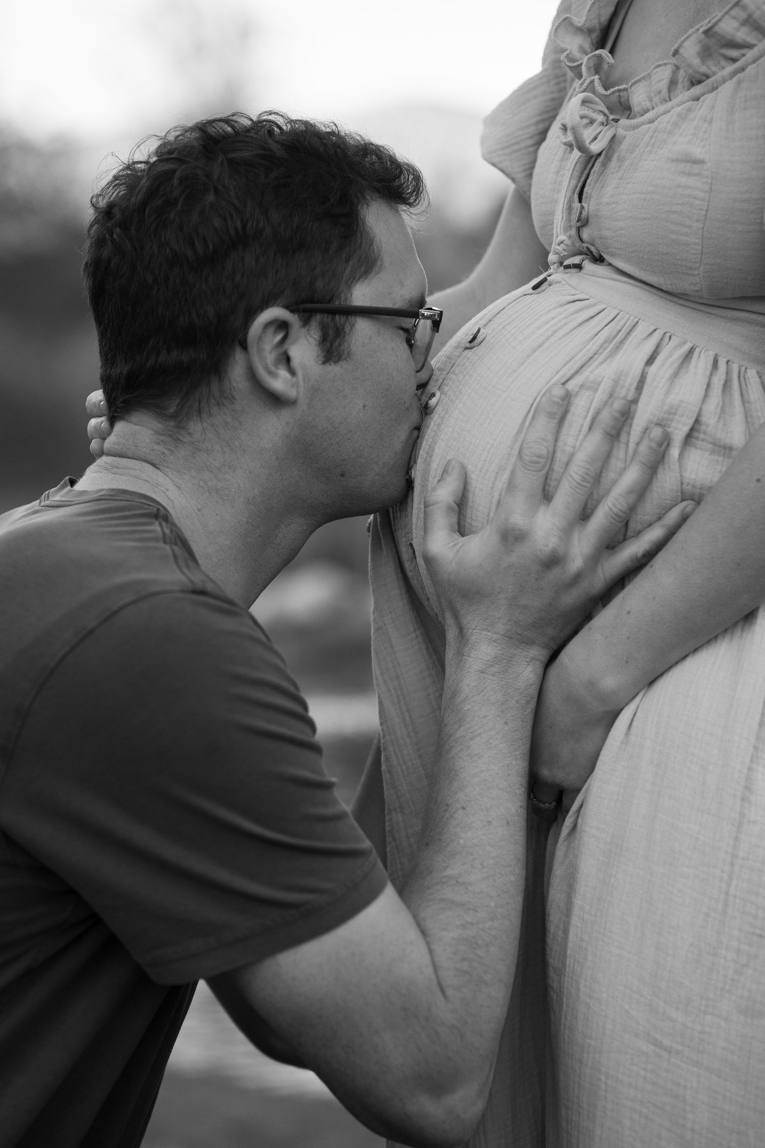 Intimate black and white maternity photography moment captured outdoors.