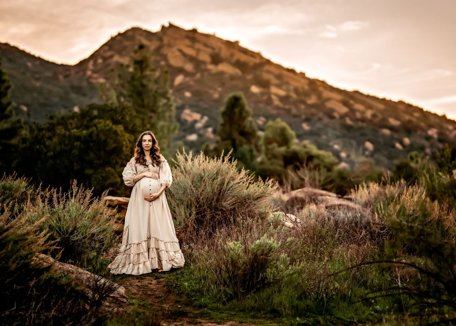 Scenic maternity photography session in mountains during golden hour.