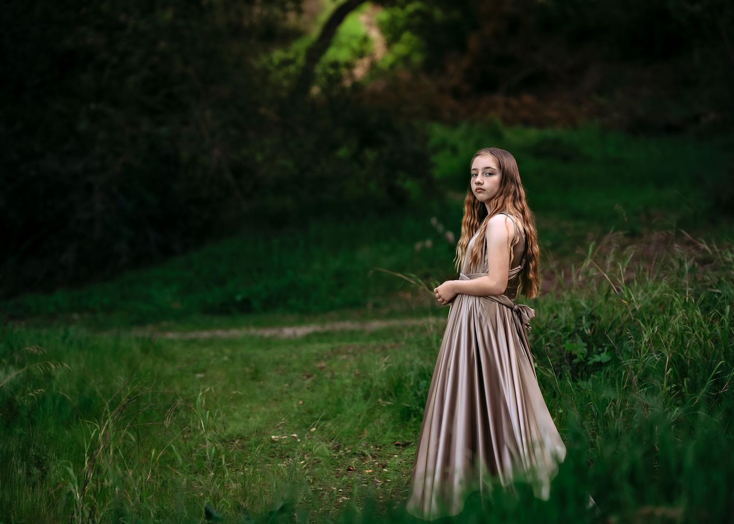 Person in a flowing mauve dress photographed in a natural outdoor setting.