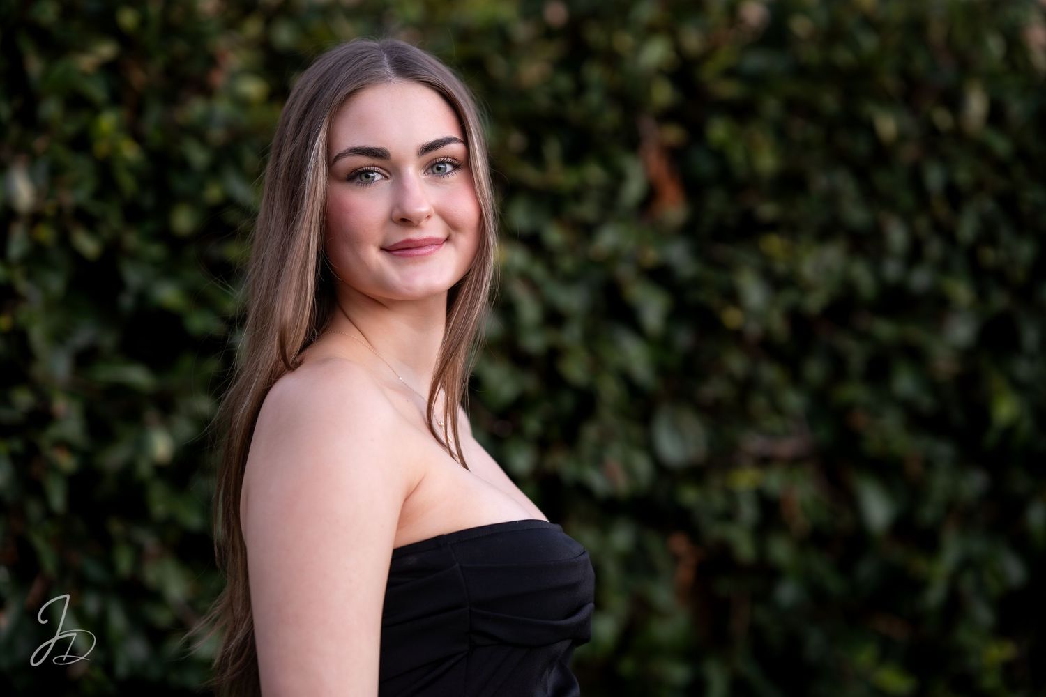 Elegant portrait session against green foliage backdrop.