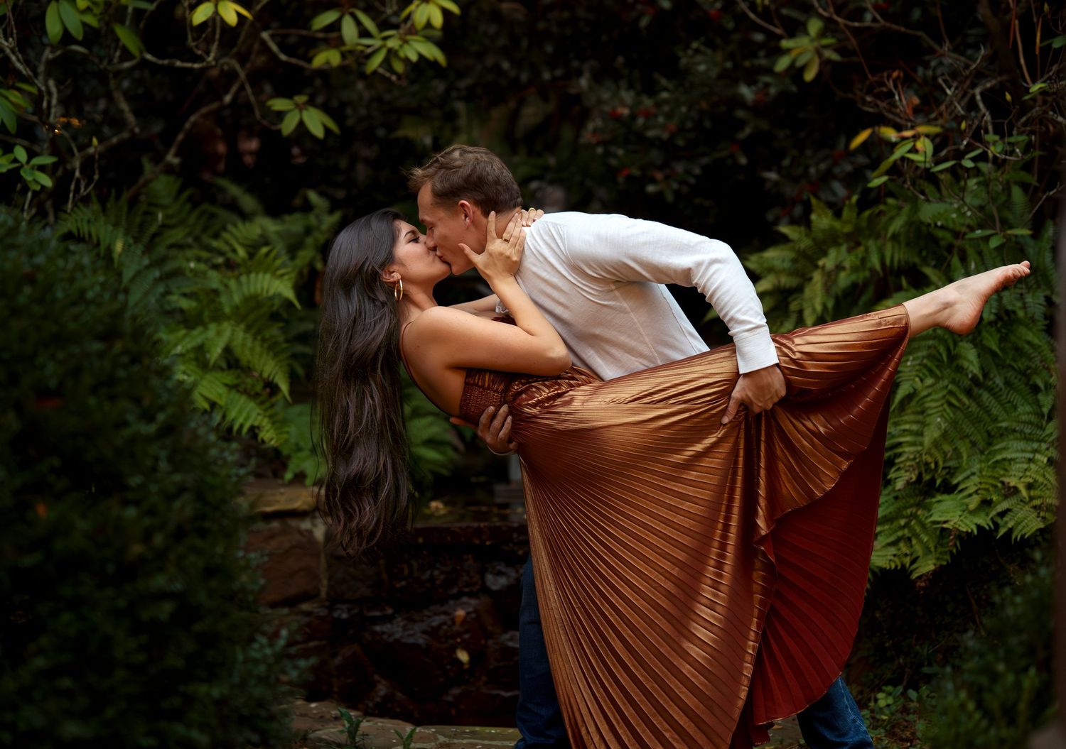 Couple dancing together in an outdoor garden setting with flowing brown dress.